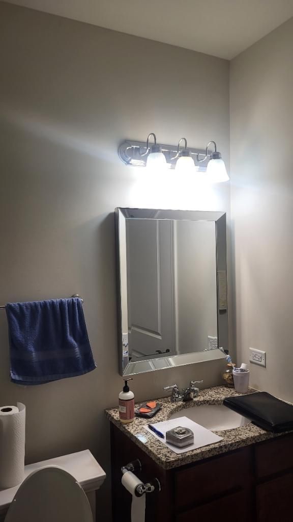 Bathroom vanity with mirror, bright light fixture, dark wood cabinet, and blue towel on the wall.