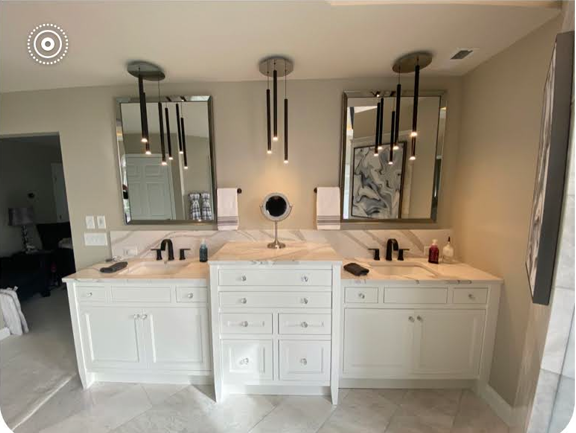 Modern bathroom with double vanity, white cabinets, mirrors, and pendant lights.