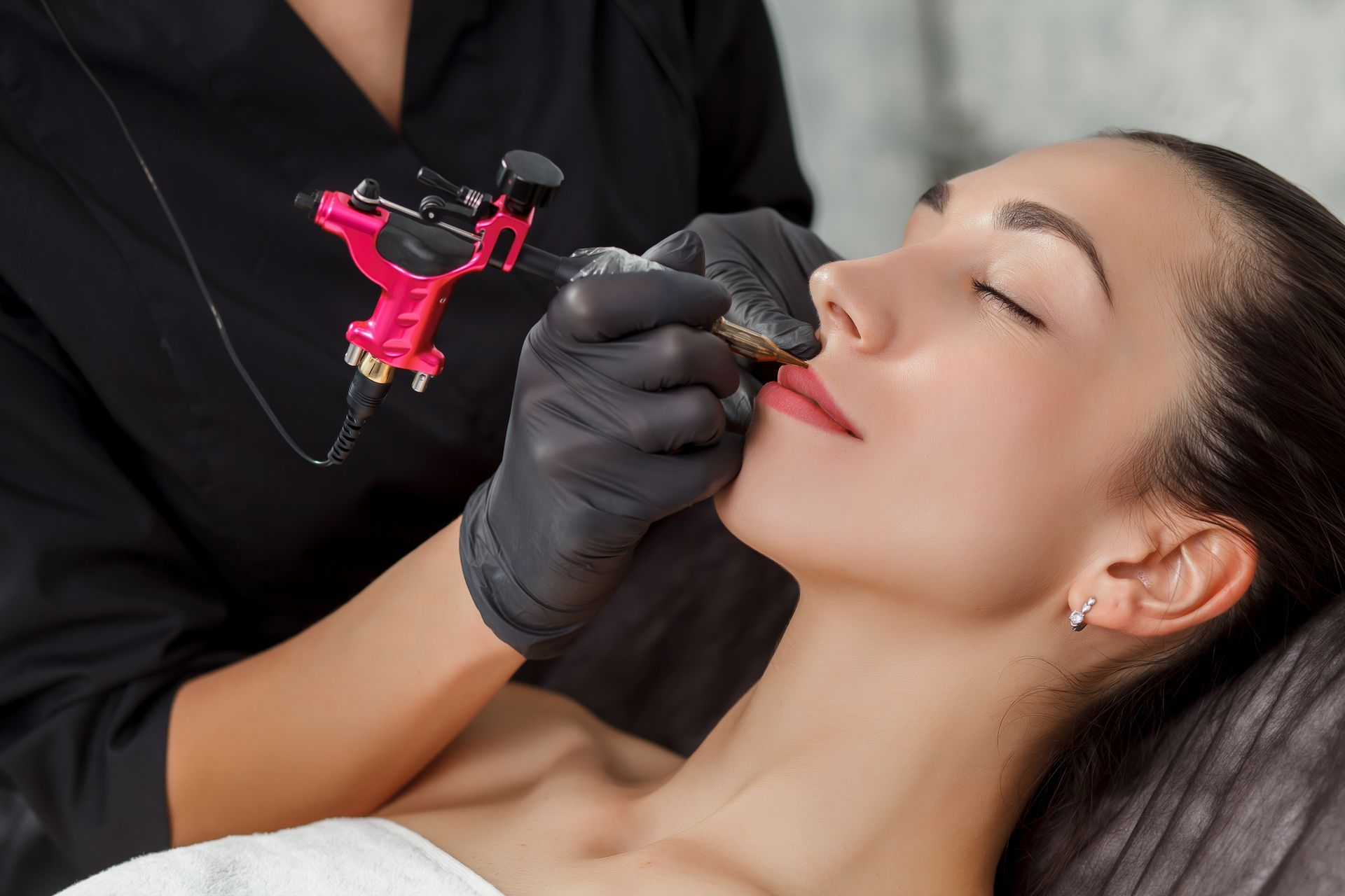 Cosmetic procedure on a woman’s lips with a tattoo-style machine during treatment