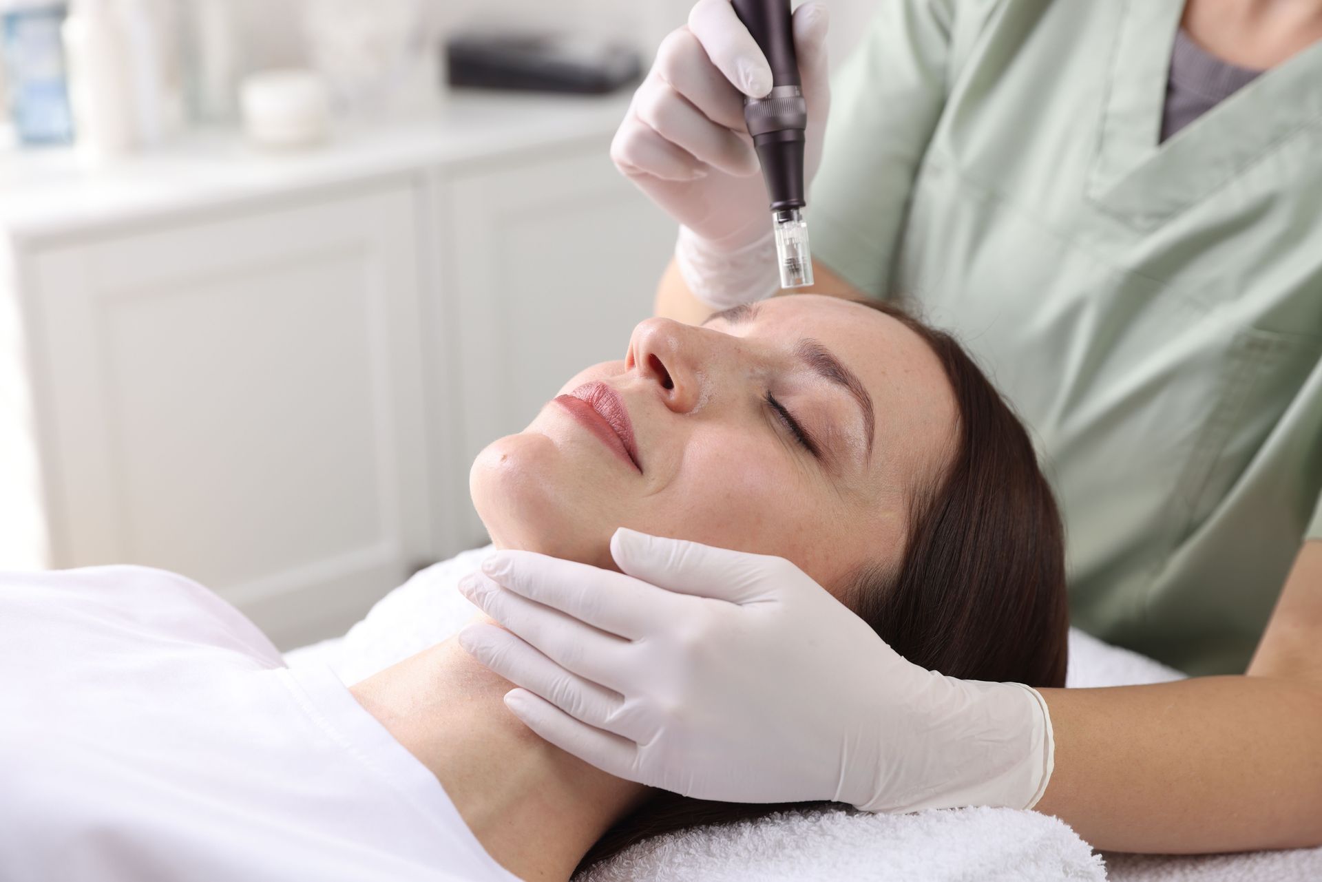 Cosmetic procedure on a woman’s face with gloved hands in a clinic setting