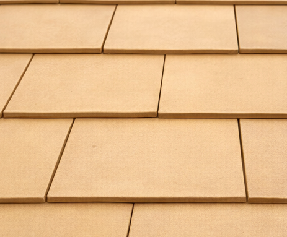 Close-up of overlapping, tan-colored roof tiles with a textured surface.