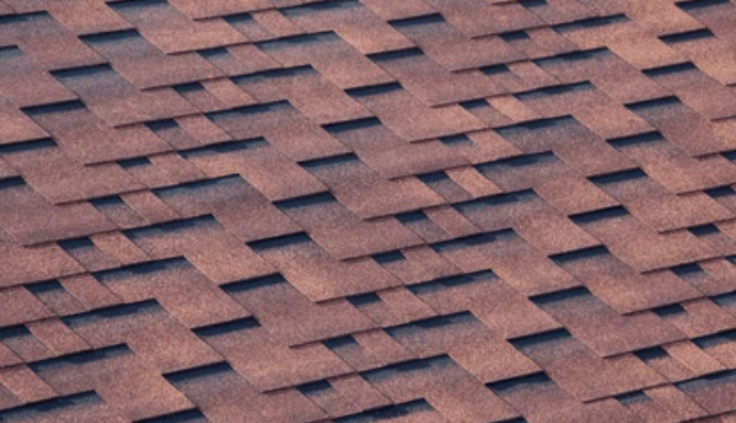 Close-up of brown and dark gray asphalt roof shingles in a zigzag pattern.