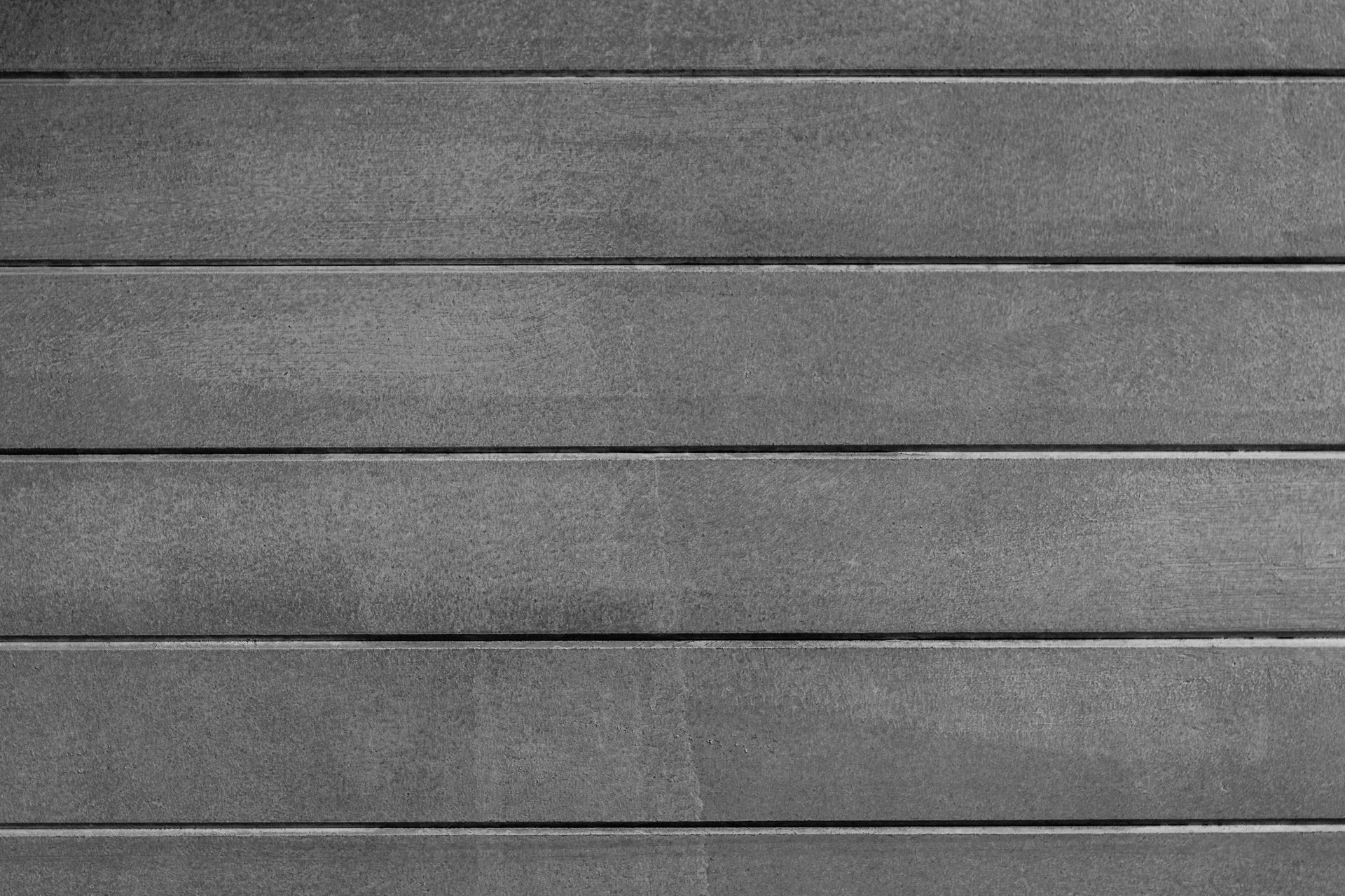 Un fond horizontal composé de dalles de béton gris à la texture visible, séparées par de fines lignes de joint sombres.