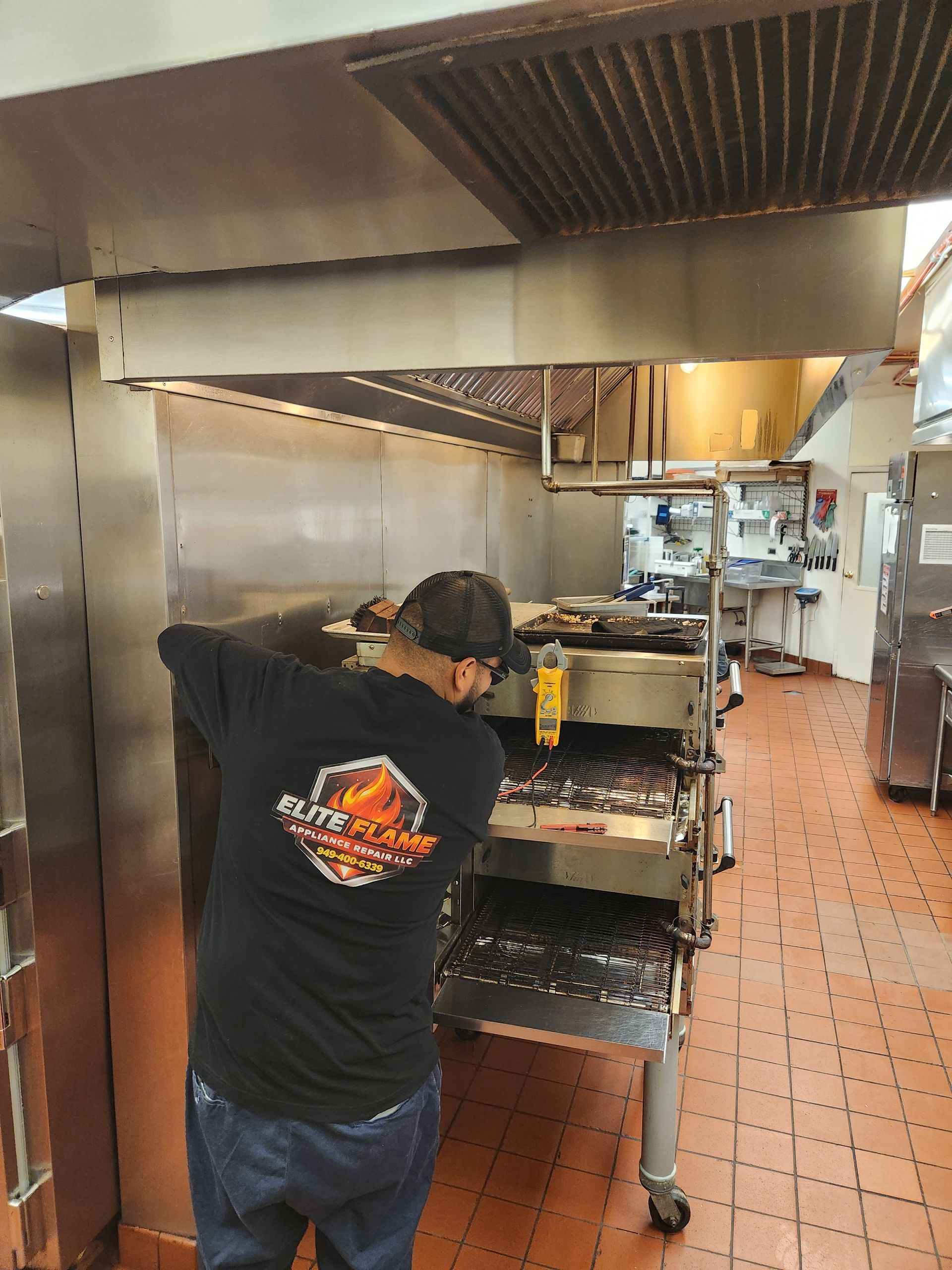 Worker in blue gloves adjusting controls on a stainless steel industrial oven in a kitchen