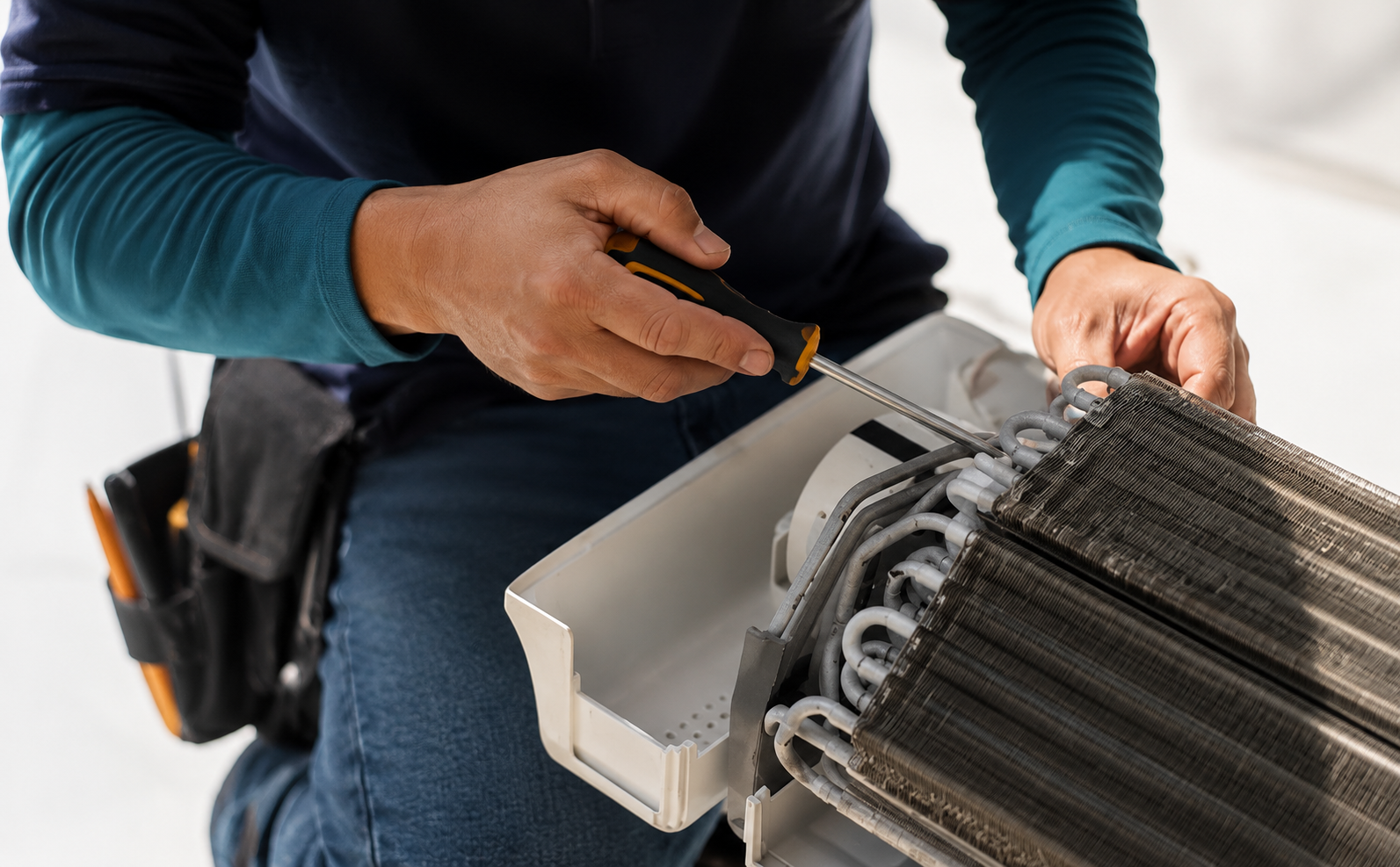Technician installing a white air filter into an HVAC unit with a screwdriver