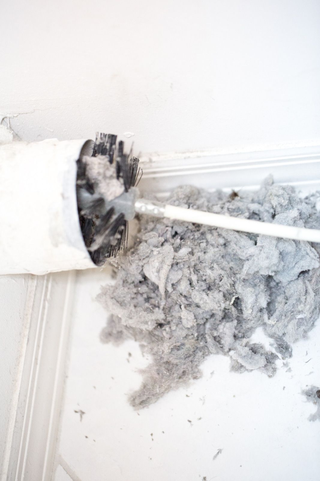 Broken white wall outlet with exposed wiring and debris on the floor