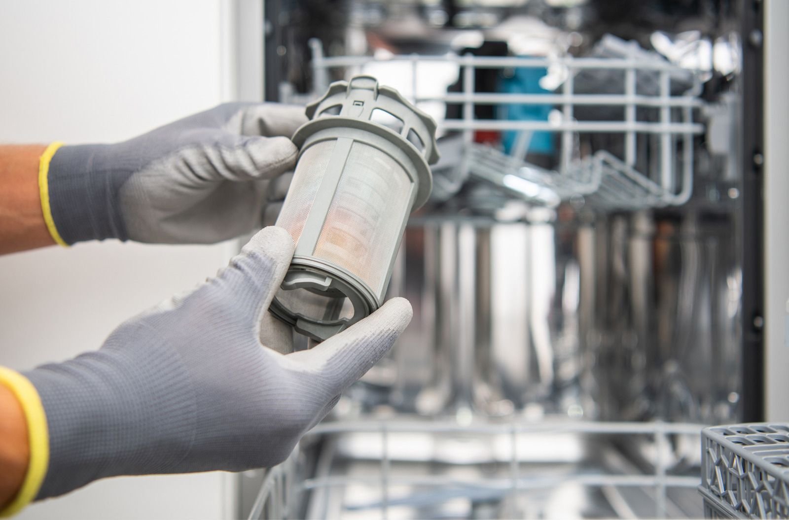 Gloved hands holding a cylindrical industrial filter in a stainless steel facility