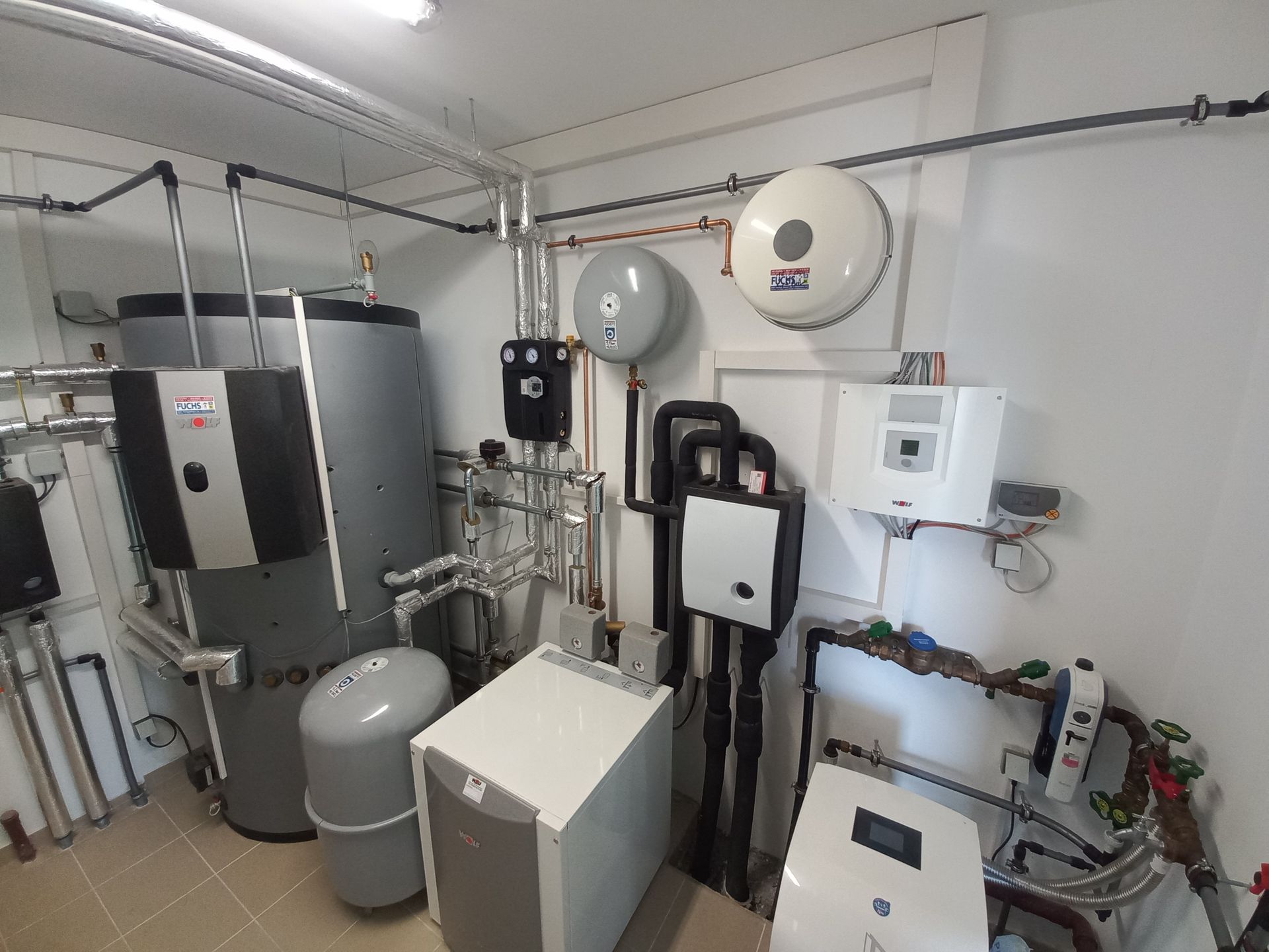 Ein Raum mit verschiedenen Warmwasserbereitungs- und Heizungsanlagen; Rohren und Tanks.