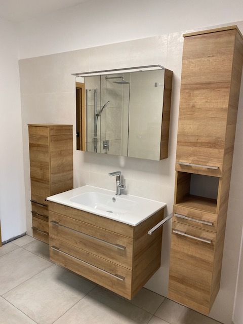 Badezimmermöbel mit Eichenschränken, weißem Waschbecken und Spiegelschrank.