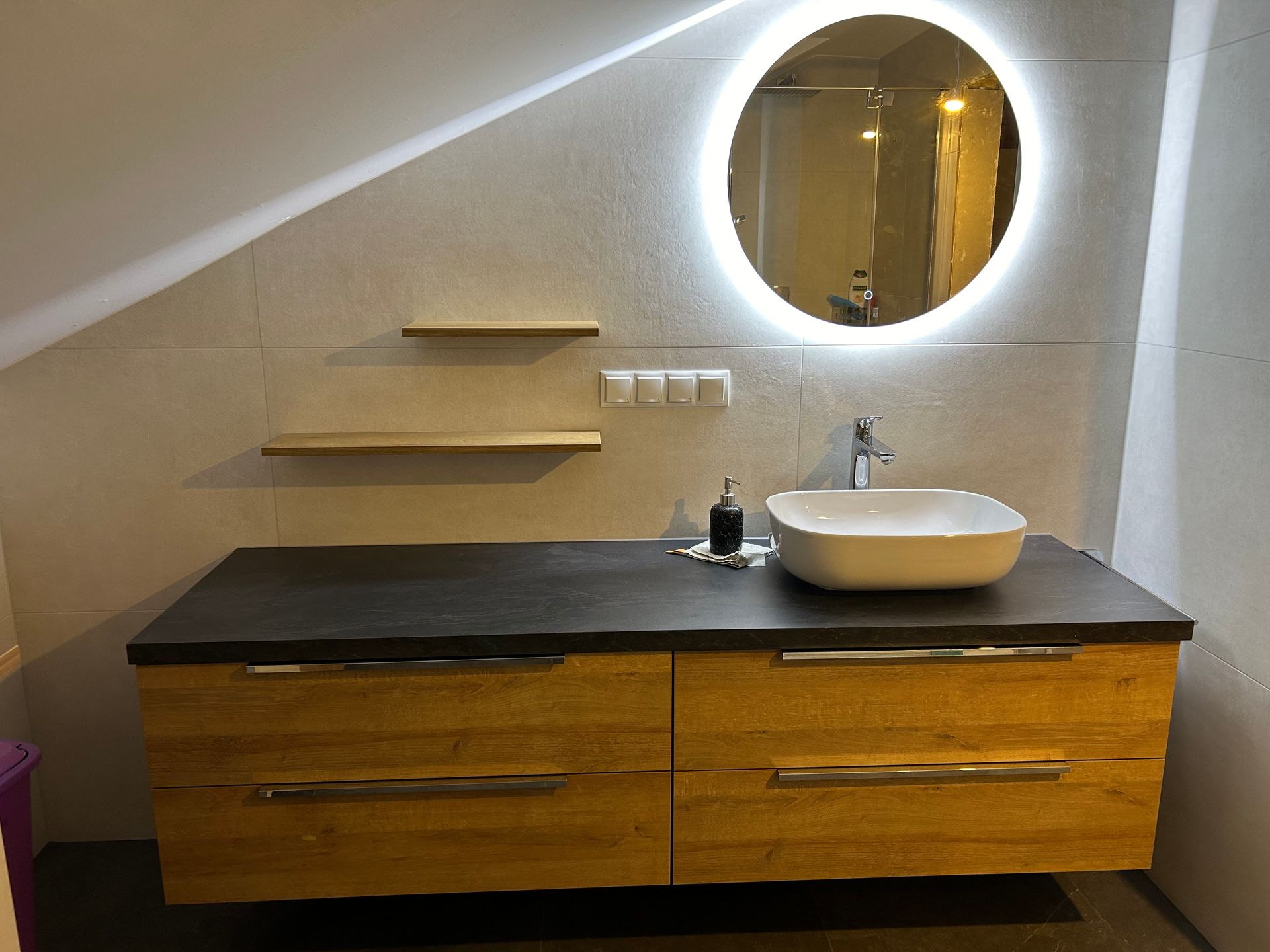 Badezimmerwaschtisch mit gelben Schubladen, grauer Arbeitsplatte, quadratischem Waschbecken und beleuchtetem runden Spiegel.