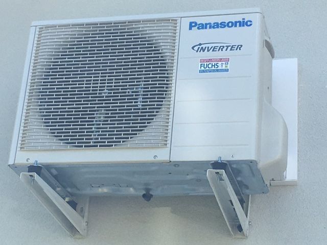 Panasonic-Klimaanlage, montiert an einer weißen Wand, gehalten von Halterungen.