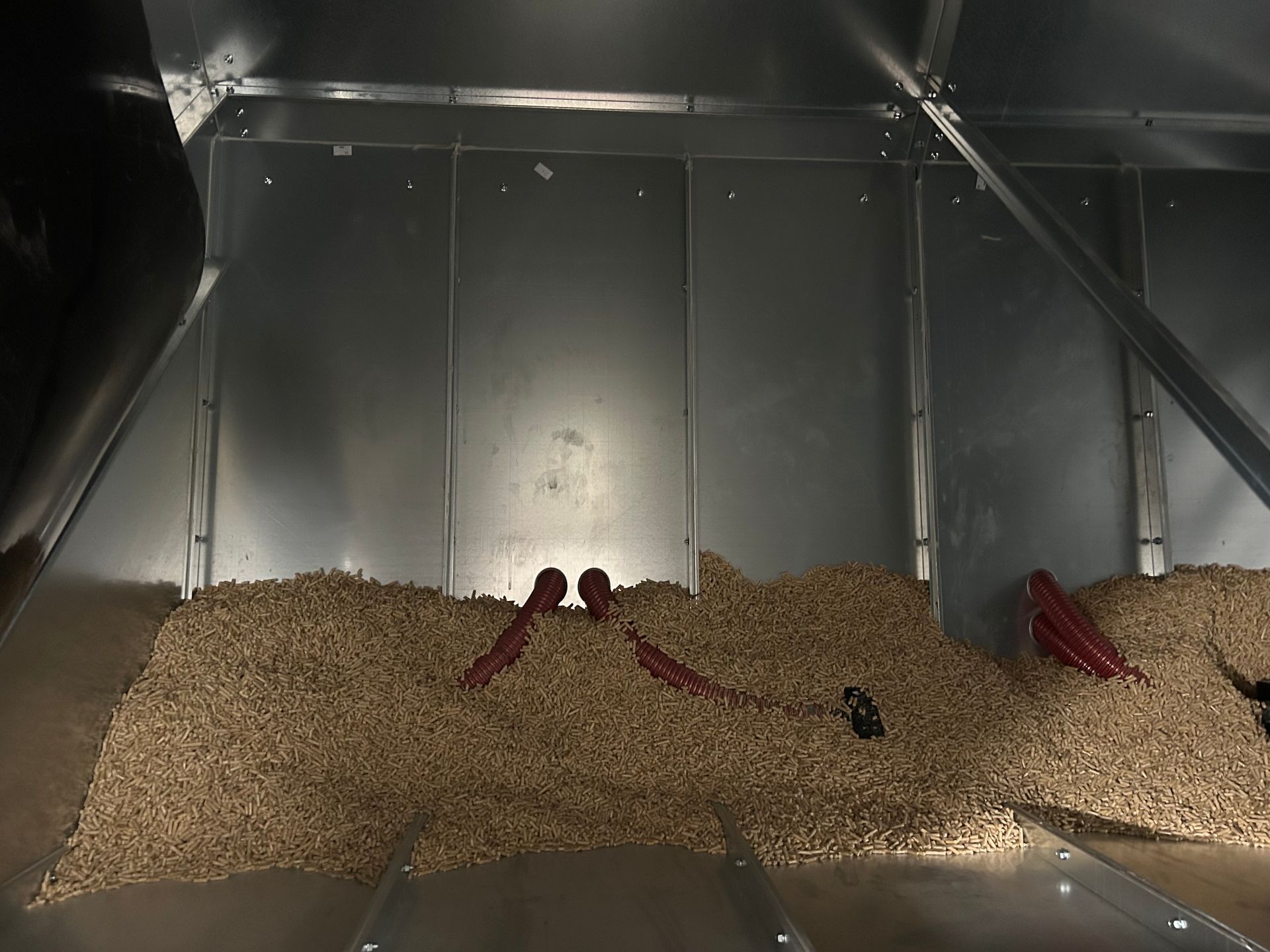 Ein mit Holzpellets gefüllter Getreidesilo, in dem sich zwei rote Zangen befinden.