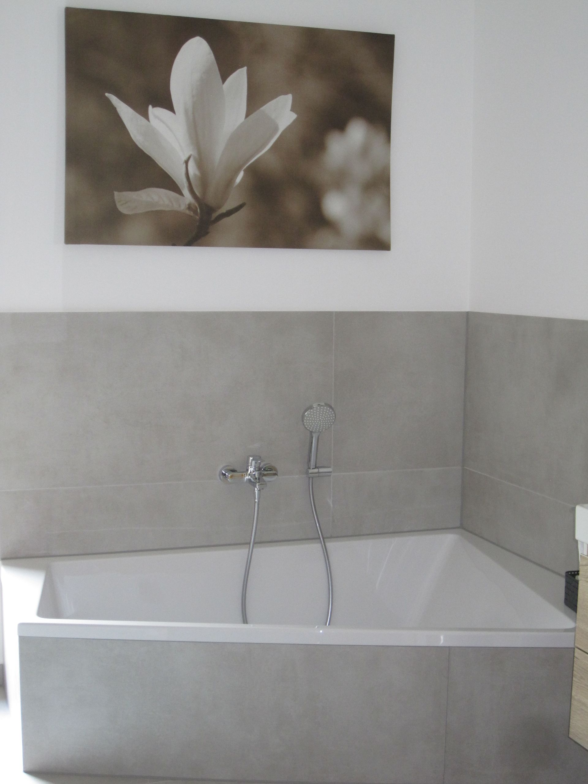 Badewanne mit grauen Fliesen und floralen Verzierungen.