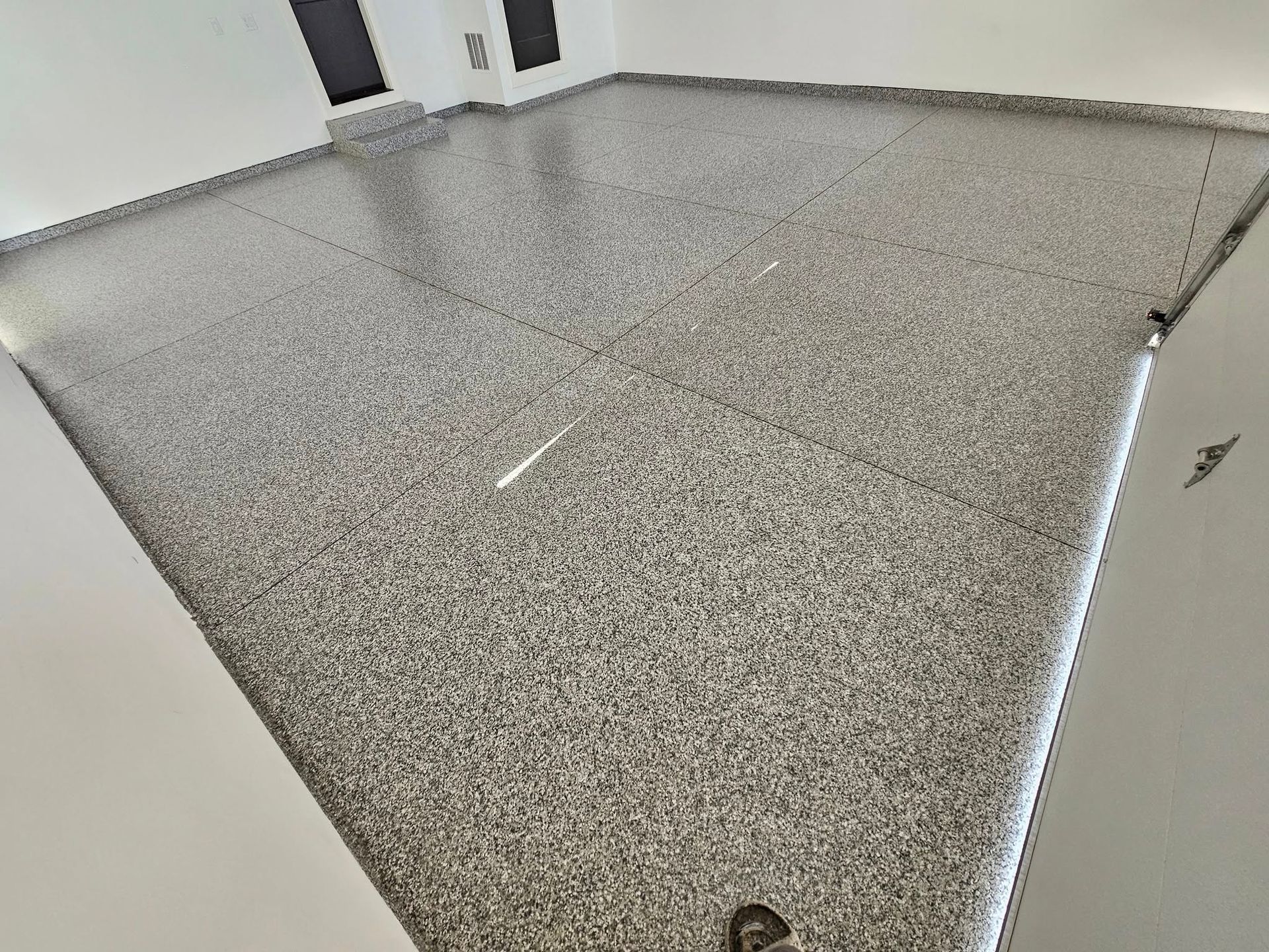 Close-up of a speckled gray countertop with seams and a white cabinet edge