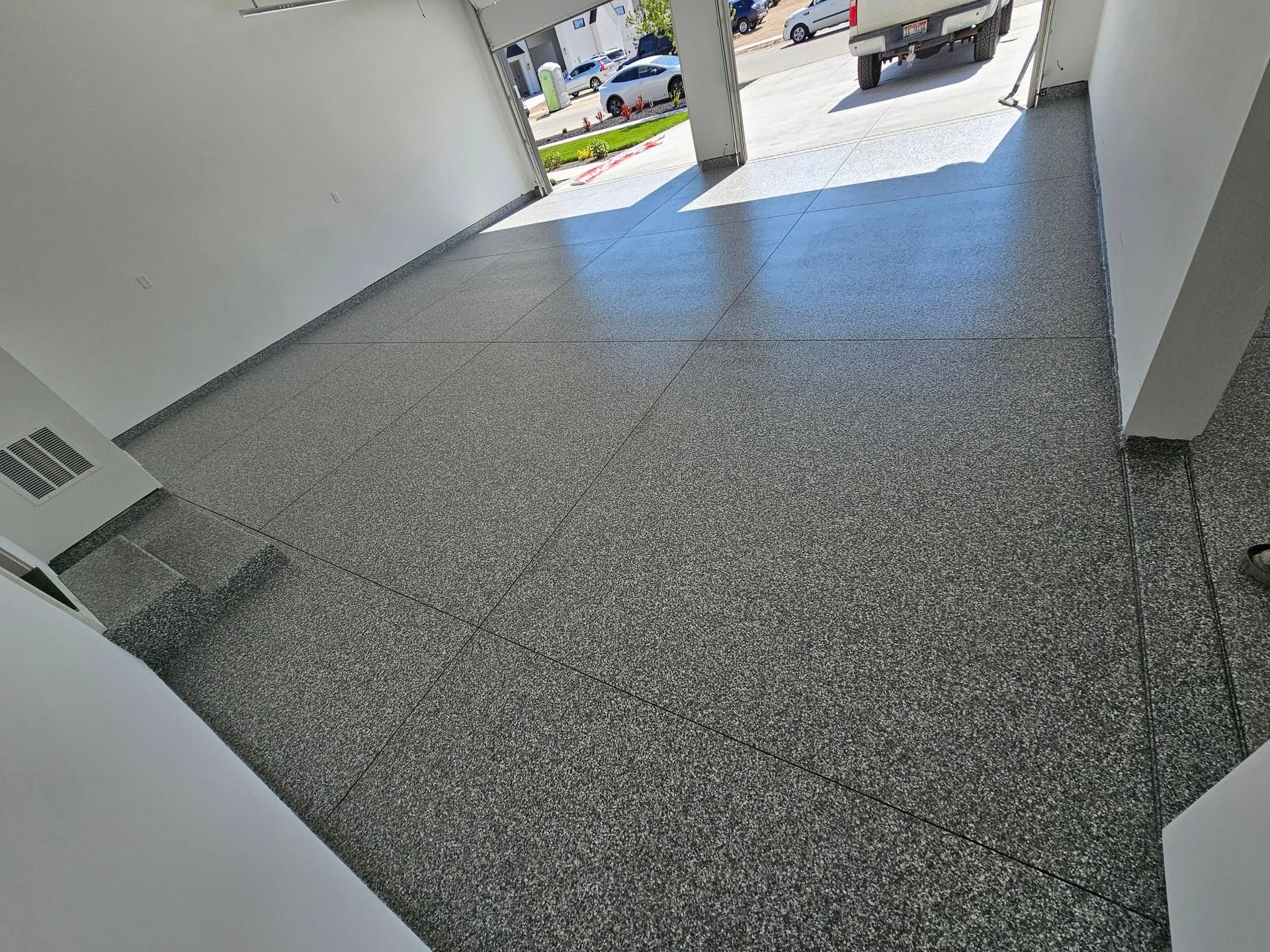 Indoor hallway with gray tiled floor leading to a bright open doorway outside