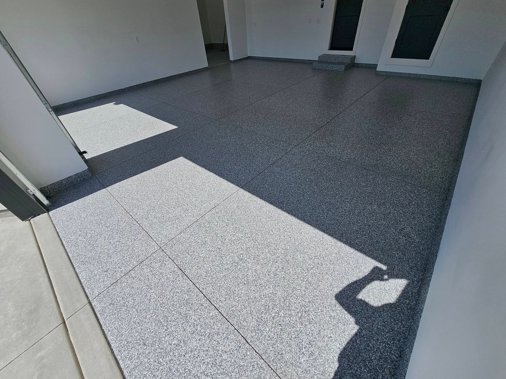 Empty tiled courtyard with sunlit and shaded areas beside a building wall