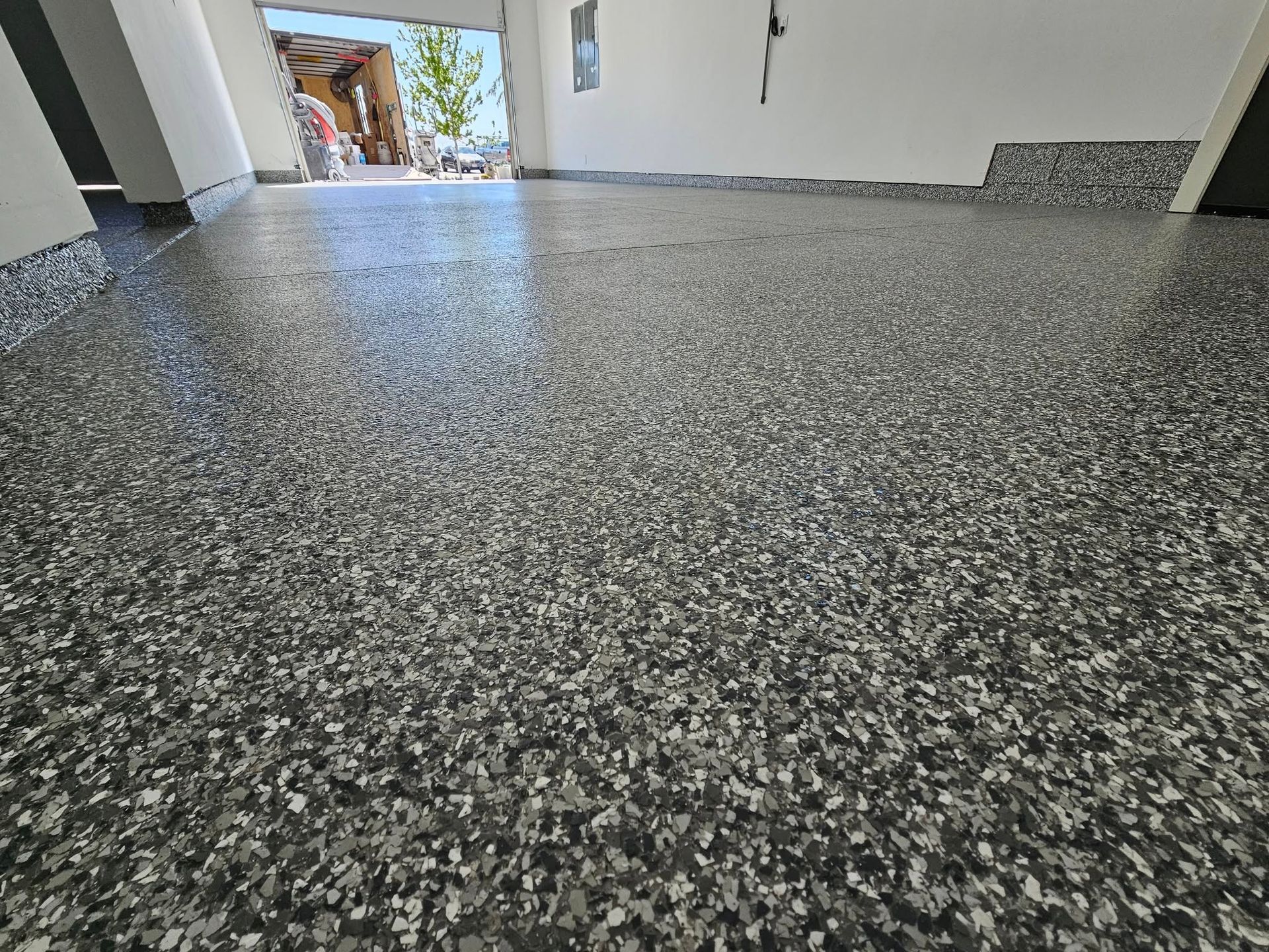 Speckled gray epoxy floor in an empty garage or room, viewed from a low angle
