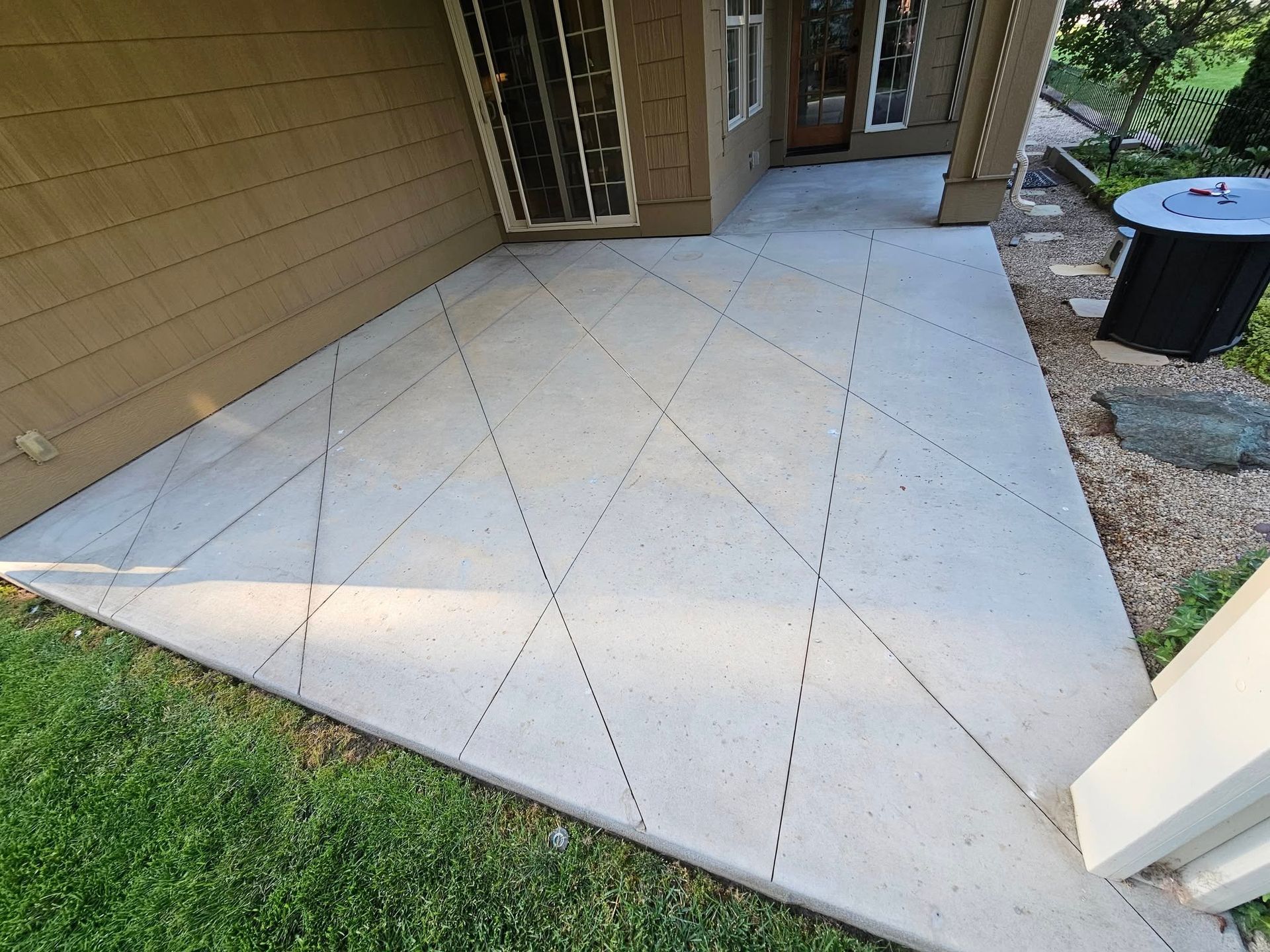 Concrete front porch with expansion joints beside a tan house and grass lawn
