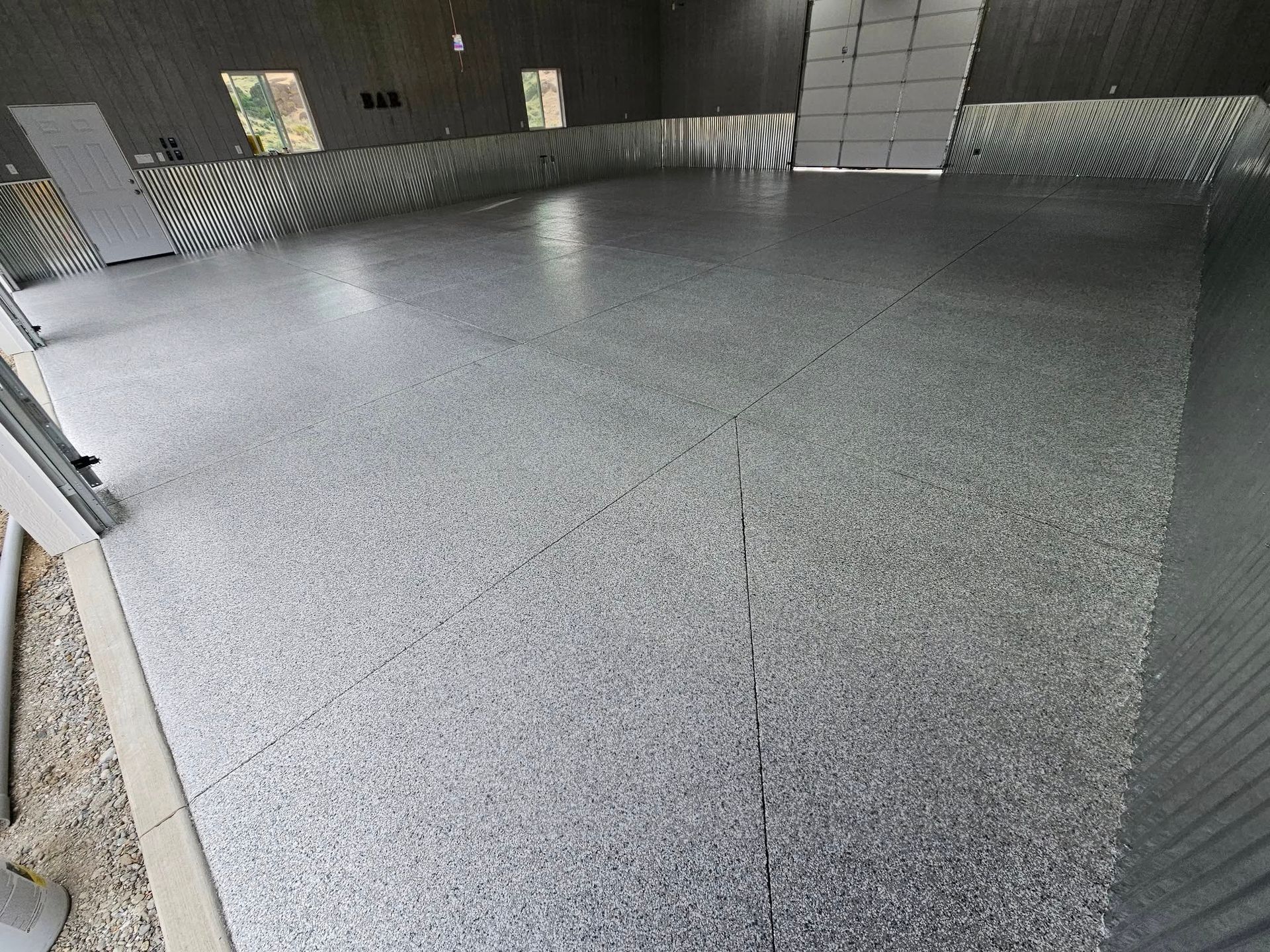 Empty industrial room with gray epoxy floor and corrugated metal walls