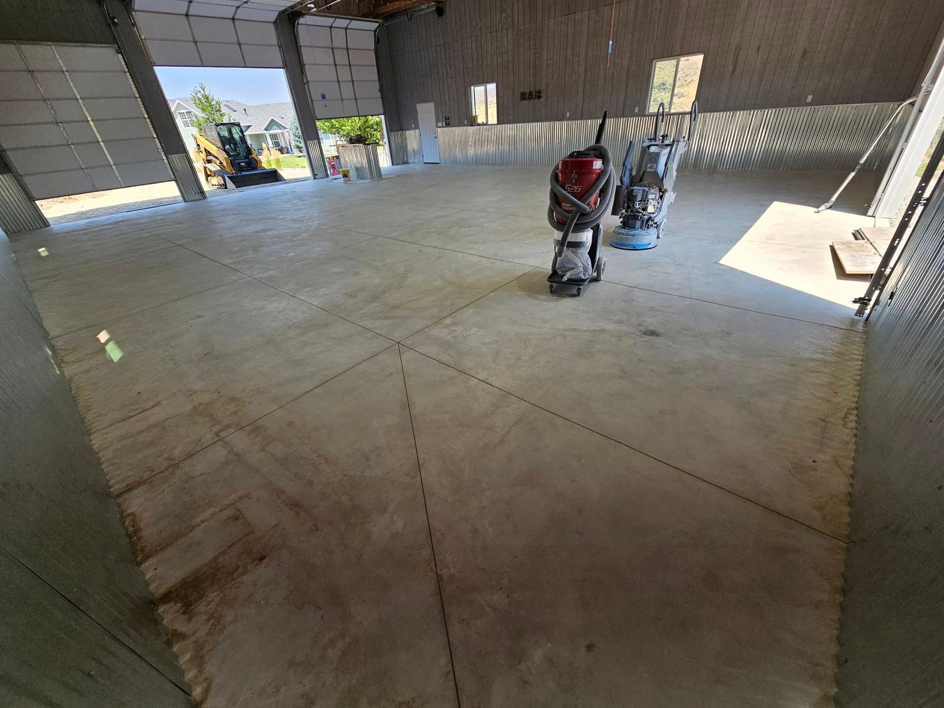 Empty warehouse floor with two industrial floor polishers near the center