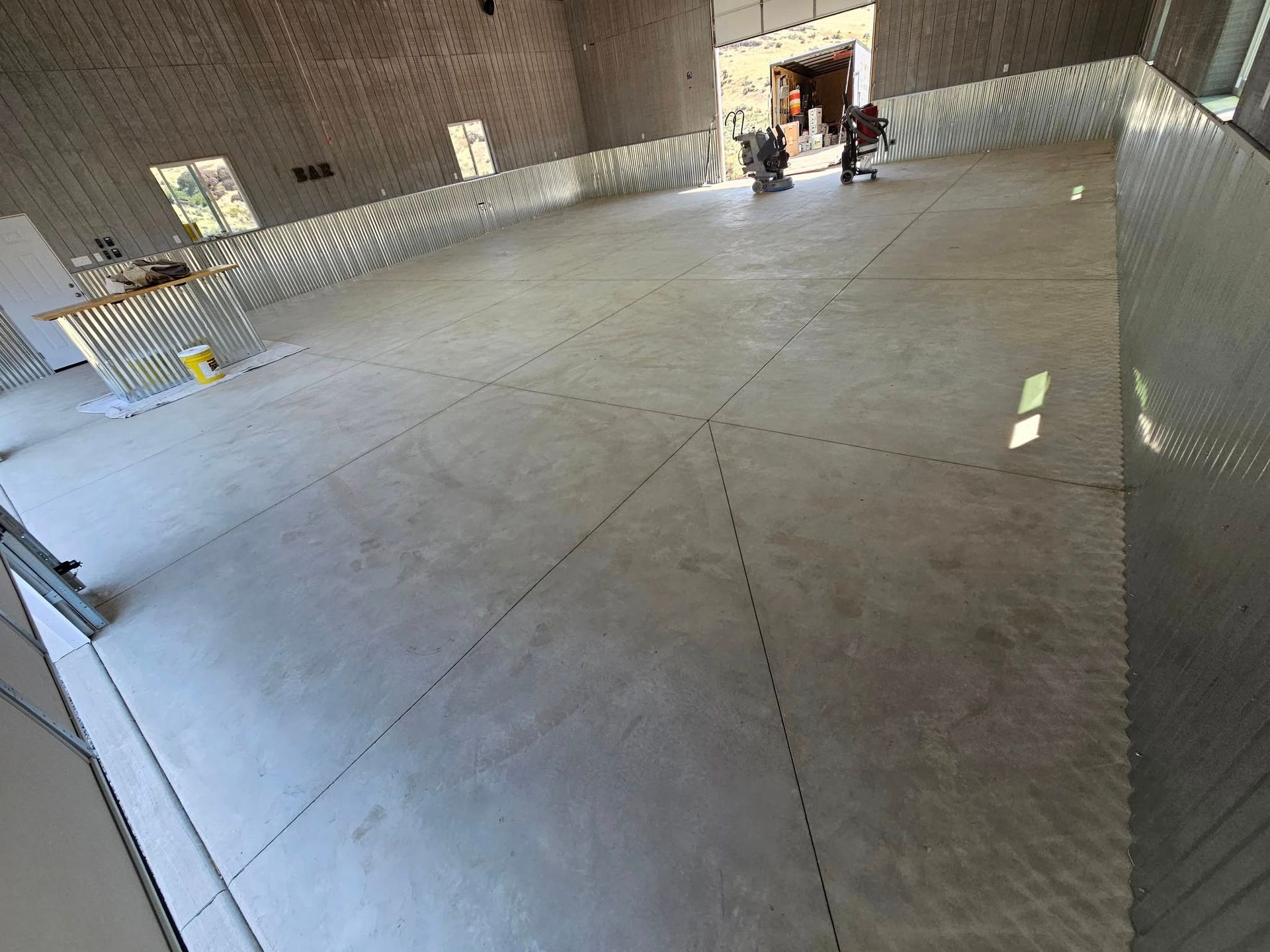 Spacious empty concrete hall with a few people standing near a bright doorway