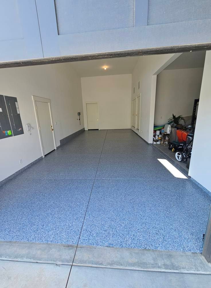 Empty blue-speckled garage with open door and stored items along the right wall.