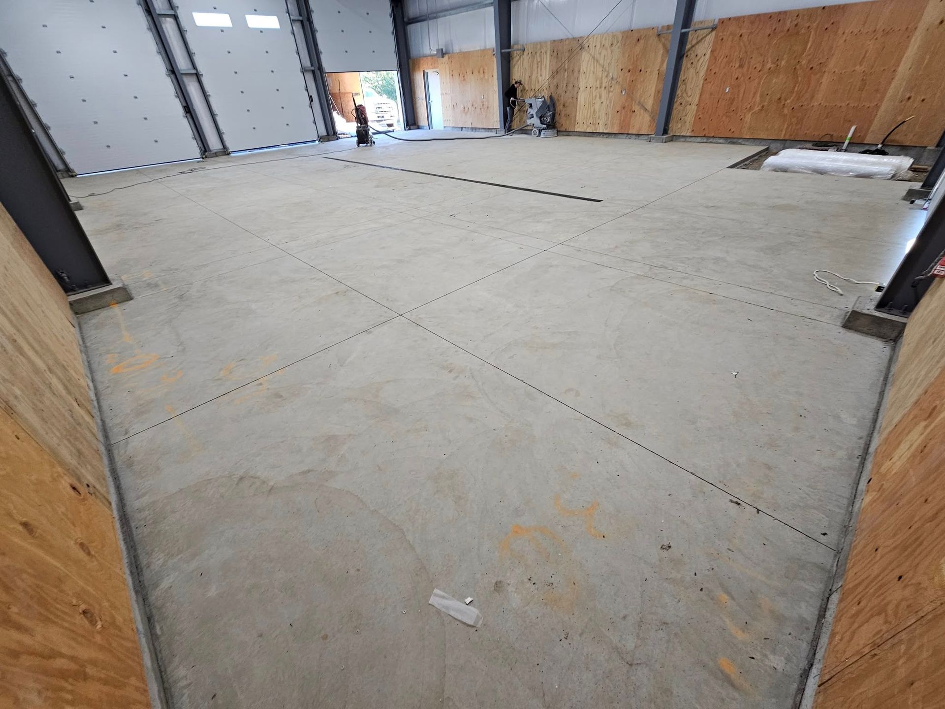 Empty warehouse interior with concrete floor, metal doors, and plywood-covered walls