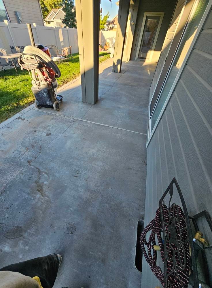 Child on a scooter in a concrete apartment walkway near a stroller and doorway
