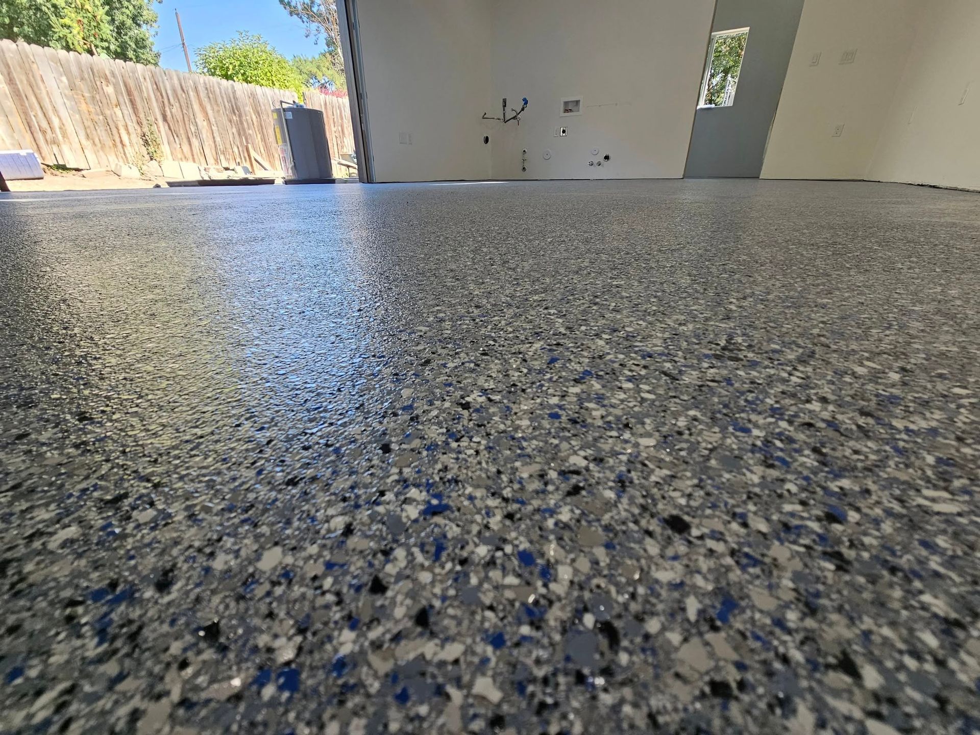 Speckled epoxy floor in a bright empty room with white walls and open doorway outdoors