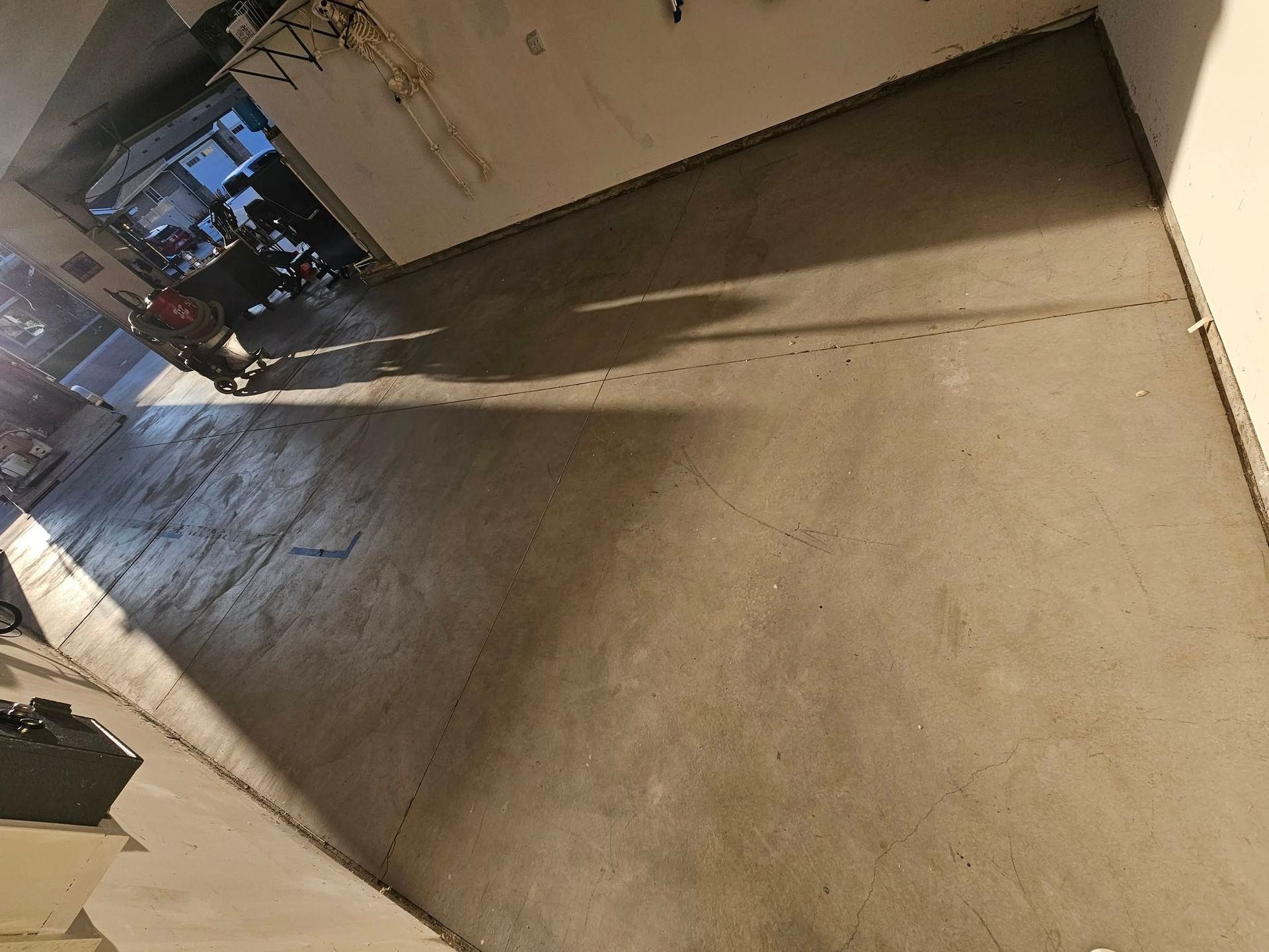 Empty concrete hallway with a person standing near the far end, lit by warm indoor light.