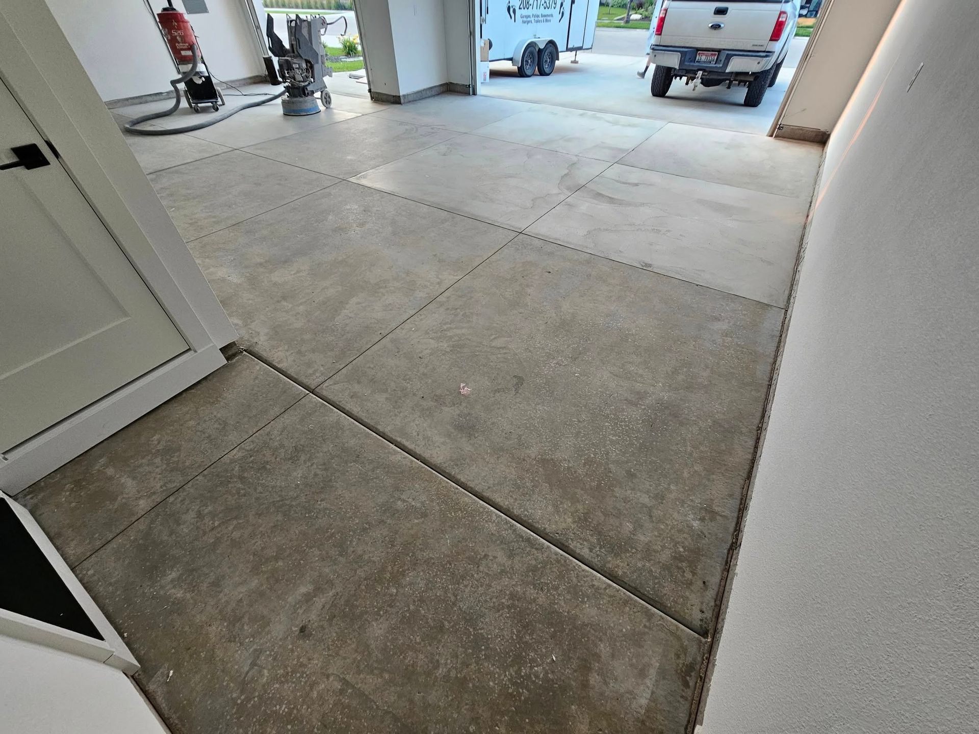 Concrete driveway leading to an open garage with a white truck parked outside.