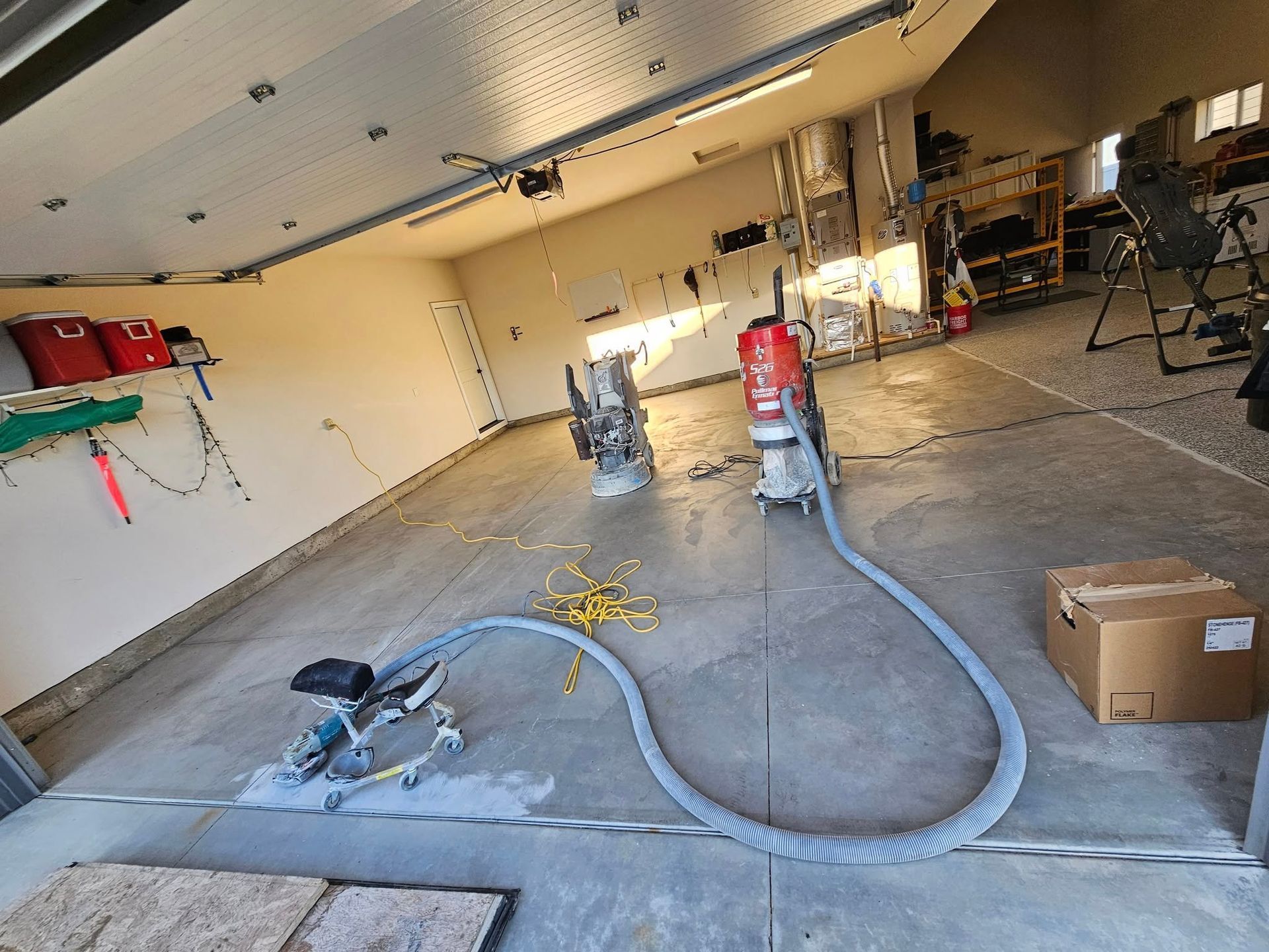 Garage interior with concrete floor, saws, air hoses, tools, and boxes during renovation work