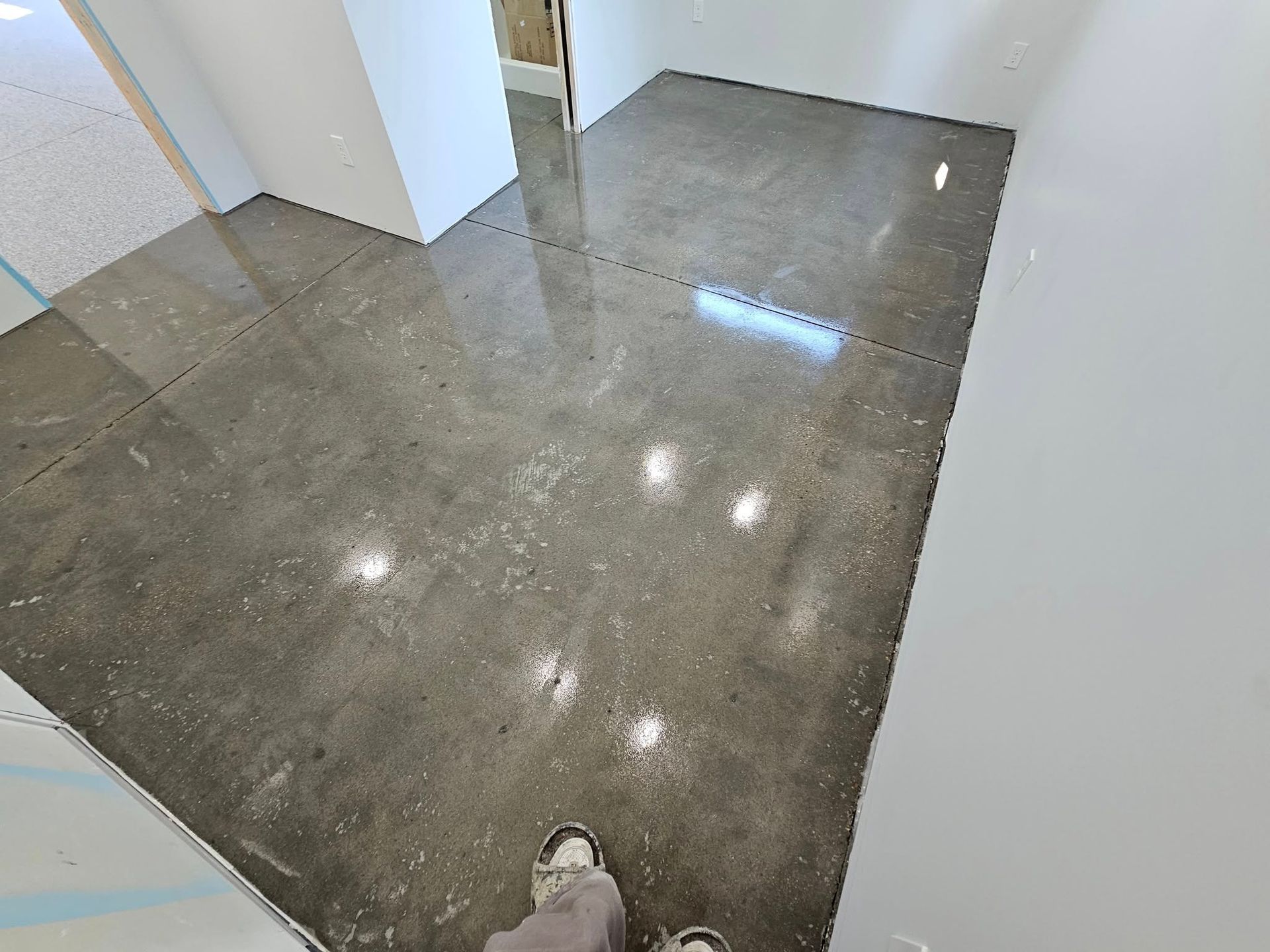 Glossy gray floor in an empty room with white walls and doorways, viewed from above