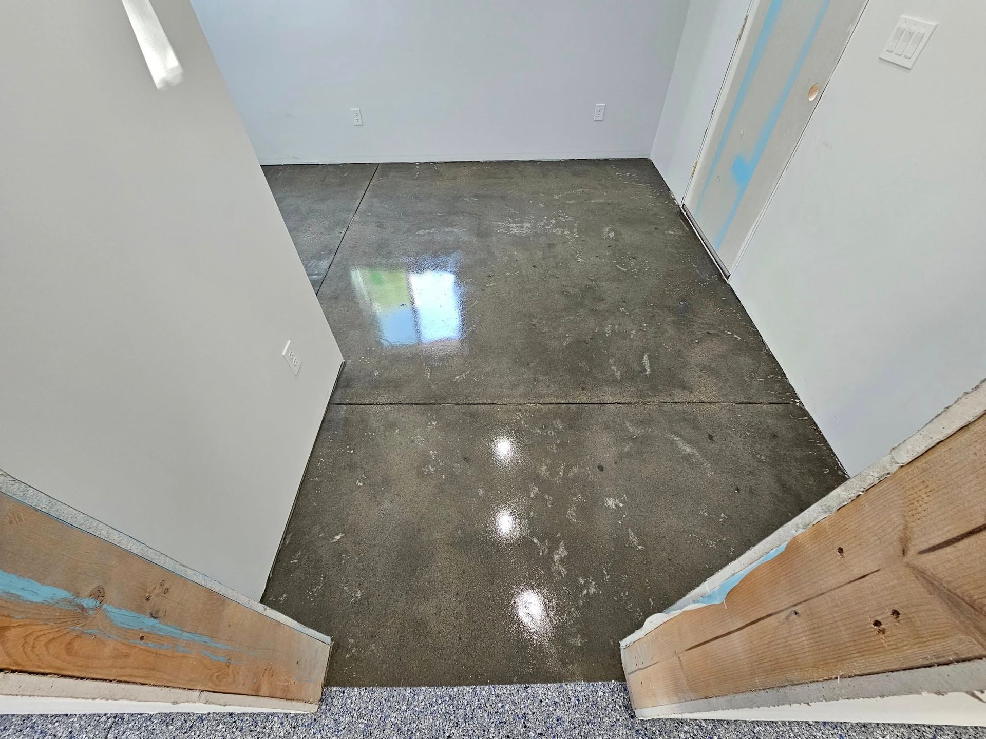 Empty doorway view into a room with a polished concrete floor and white walls.