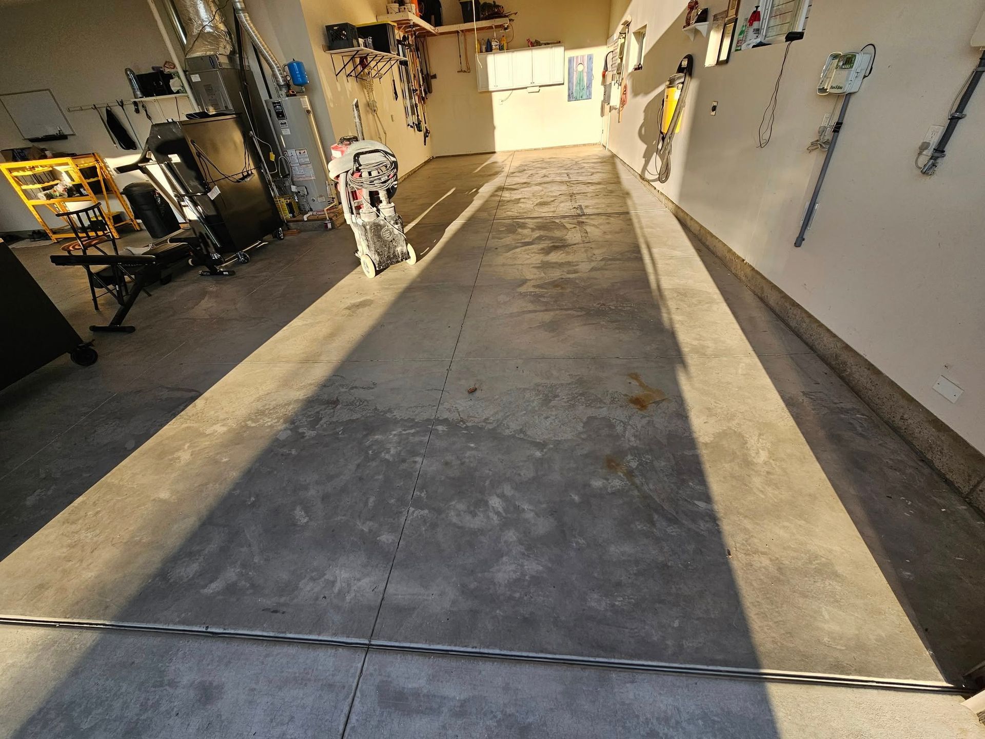 Long industrial hallway with a robot on the left and a wet concrete floor with sunlight shadows.