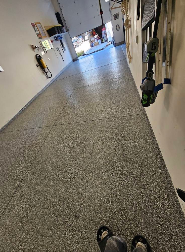 Long indoor hallway with white walls, gray floor, and a bright exit at the far end.