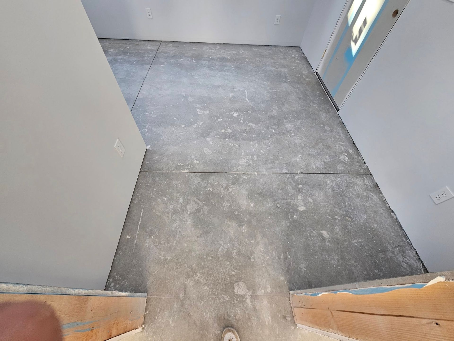 Empty room with unfinished concrete floor and open doorway at the bottom of stairs