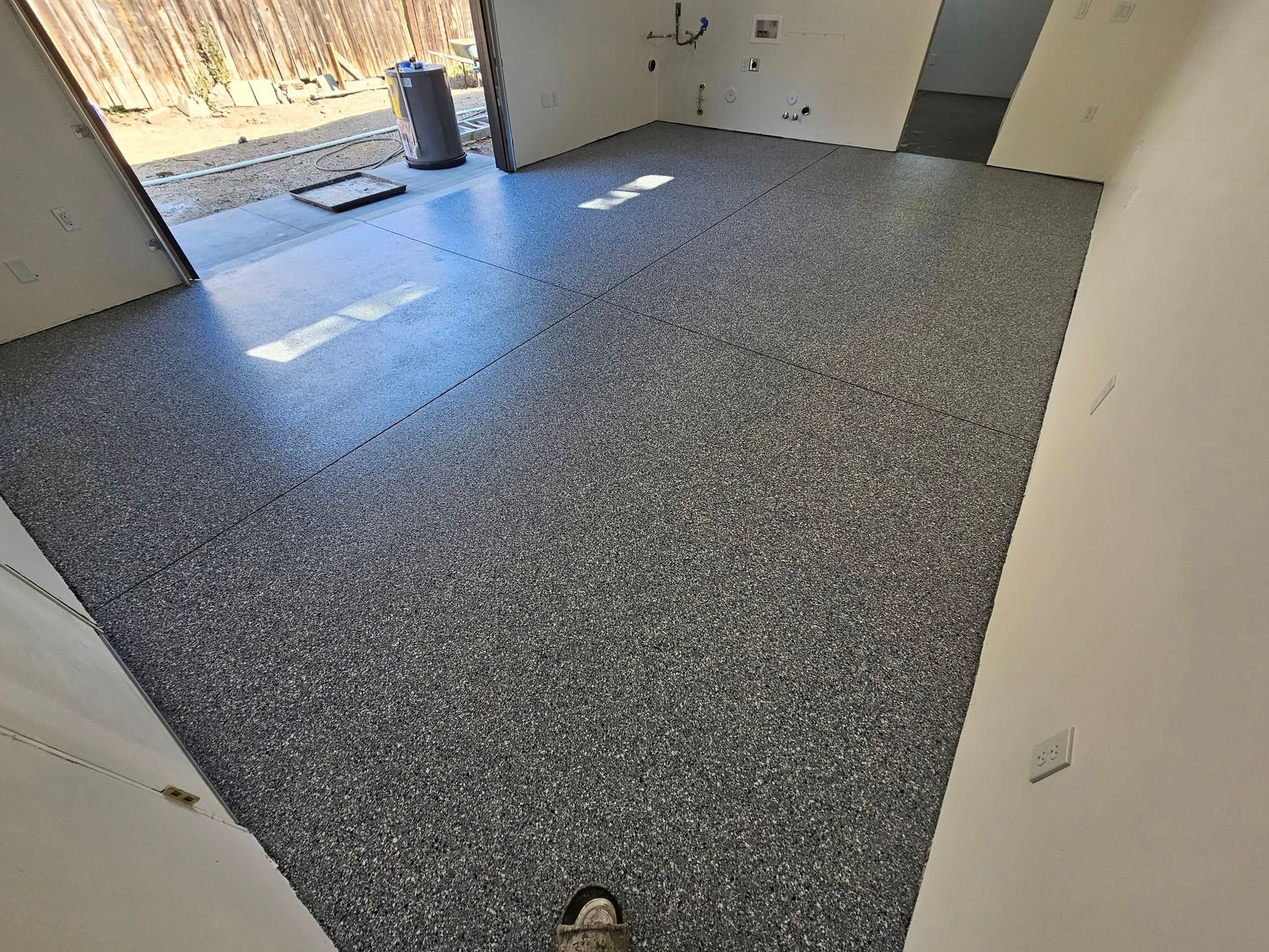 Empty room with gray carpet, white walls, and sunlight near a doorway