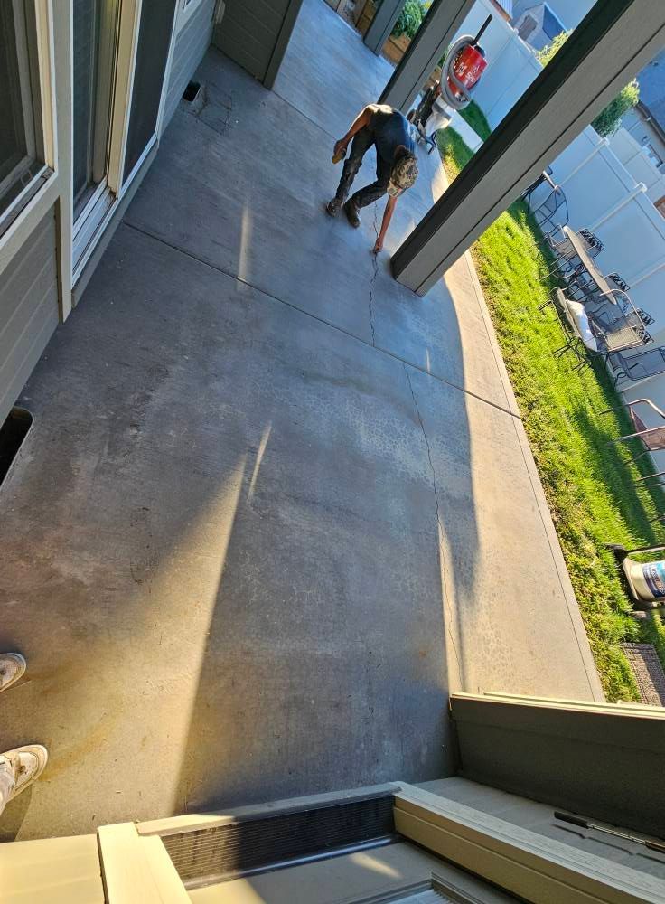 Two people on a building walkway beside a stairwell, with a street and greenery below