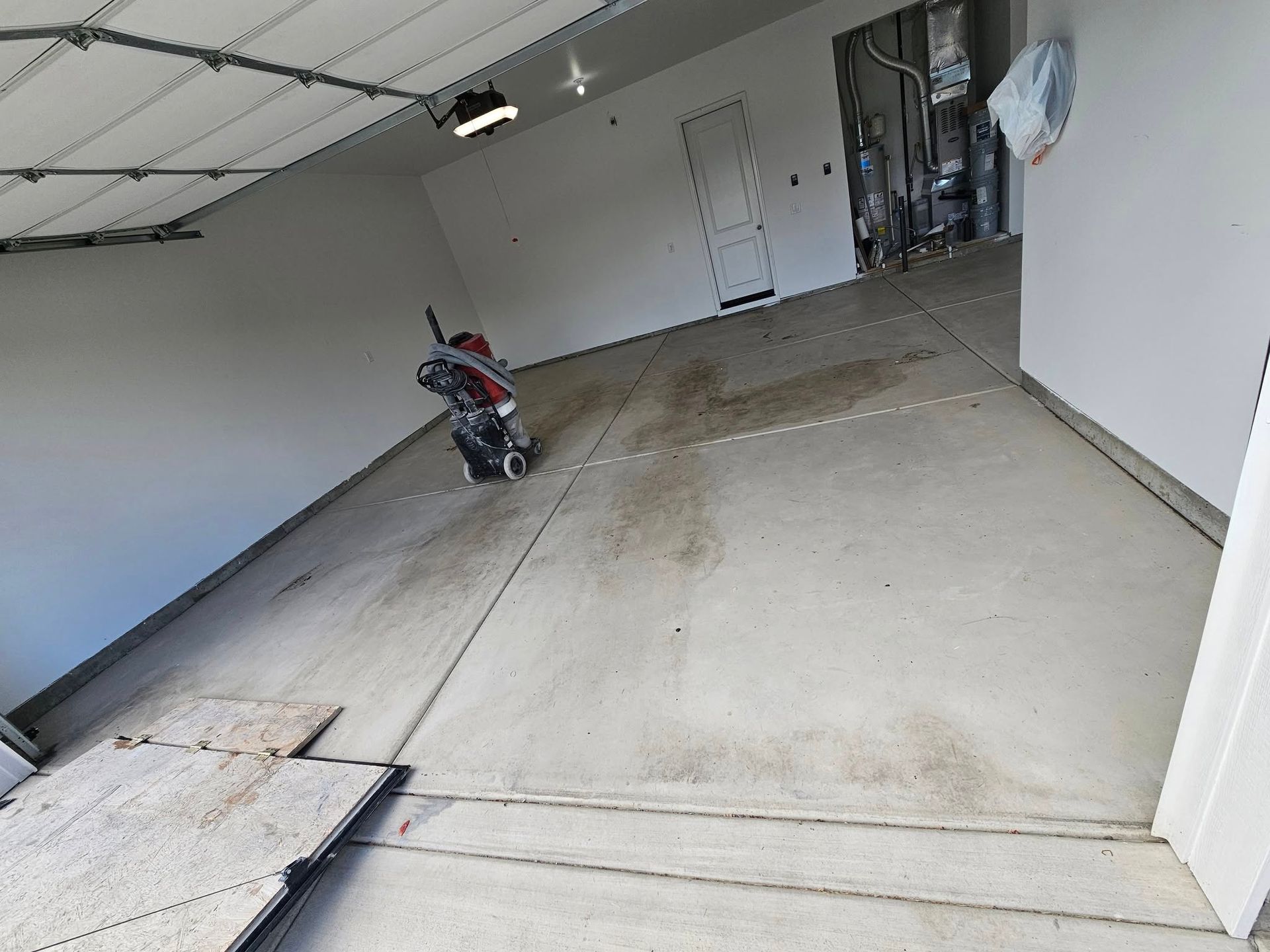 Empty garage with a motorcycle parked near the back wall and a concrete floor.