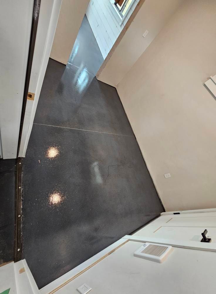 Narrow hallway with dark tile floor, white walls, and bright light reflecting near a doorway