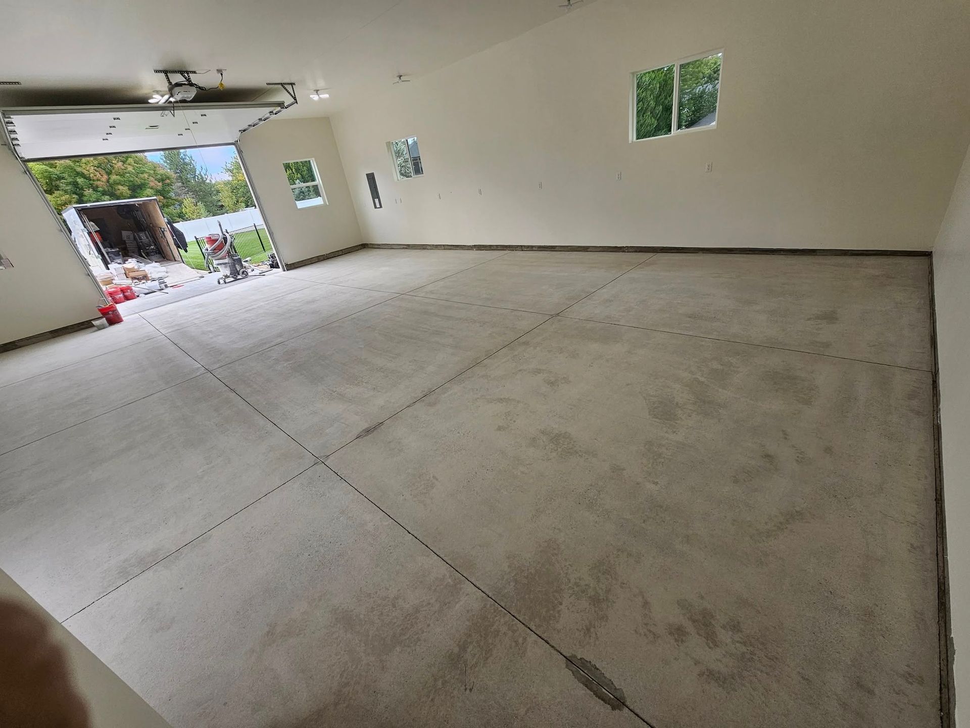 Empty concrete garage with a smooth floor and small windows, viewed from the open doorway