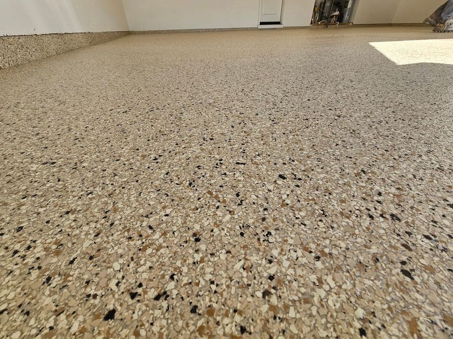 Speckled terrazzo floor in a bright indoor room with sunlight near the wall