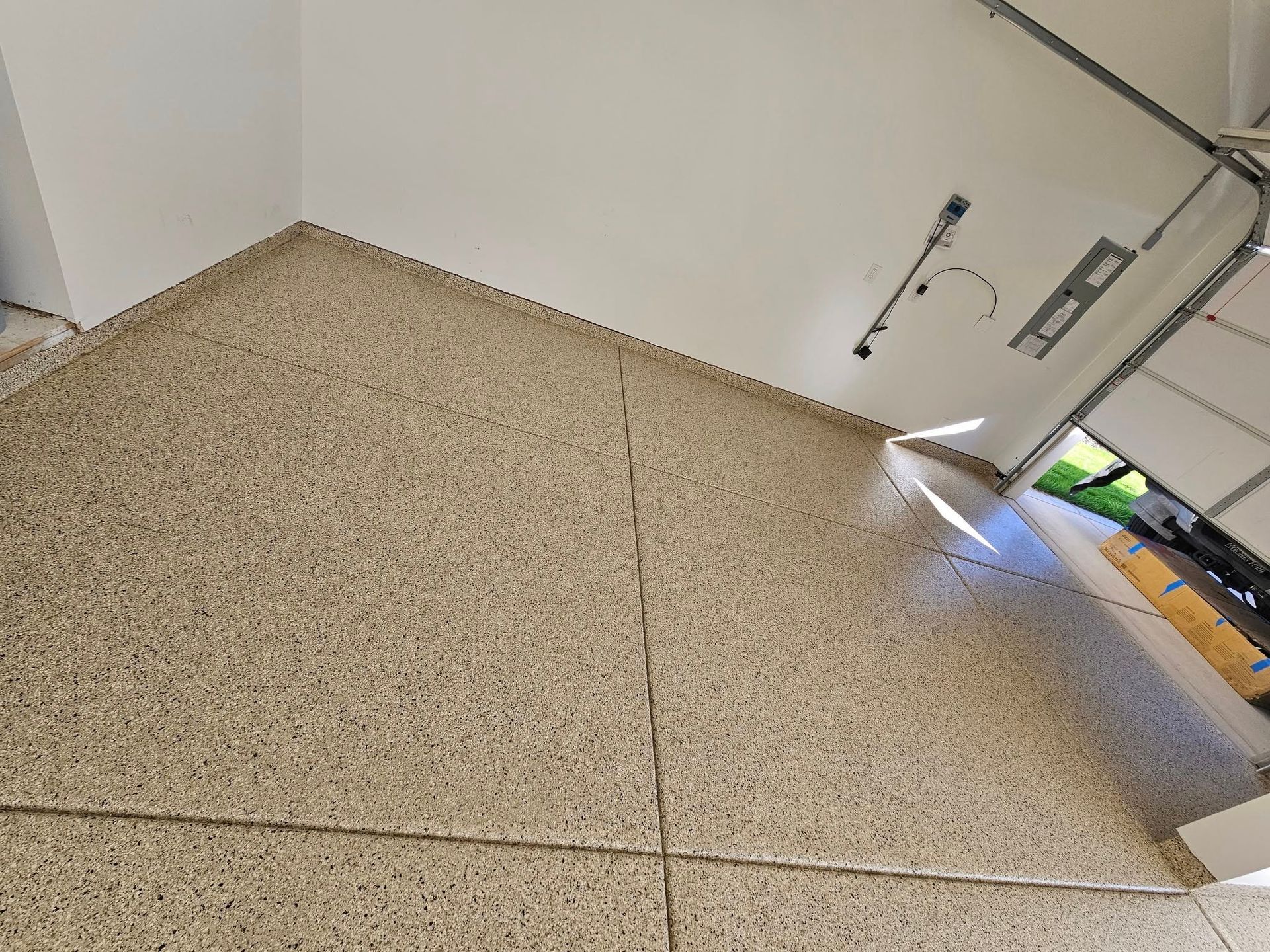 Tilted view of a tiled floor and white wall with a partially open door letting in bright light