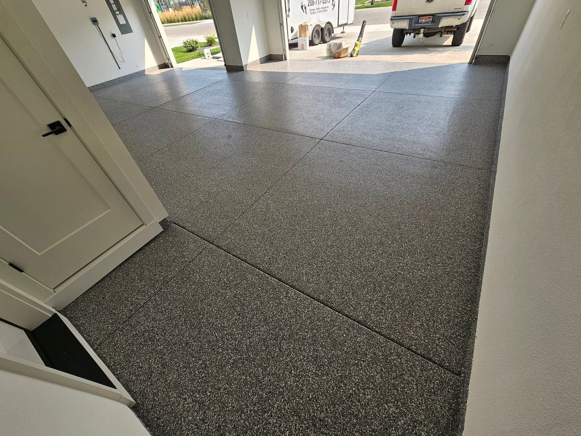 Speckled gray garage floor leading to an open driveway with a pickup truck outside
