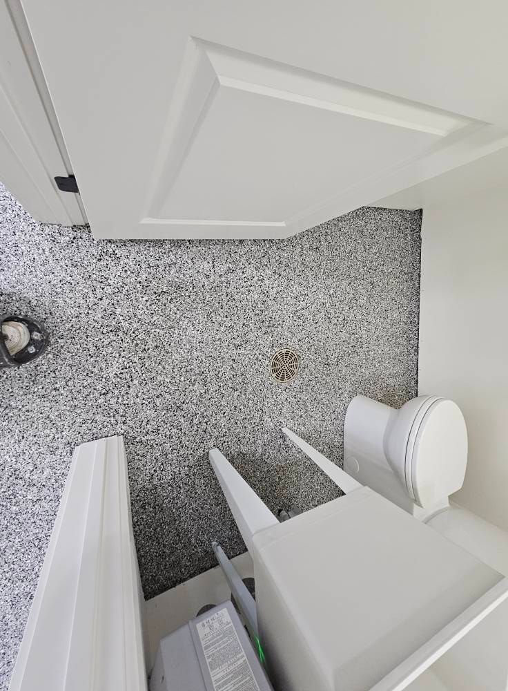 White door opening to gray speckled floor, with part of a white chair or cabinet in the foreground
