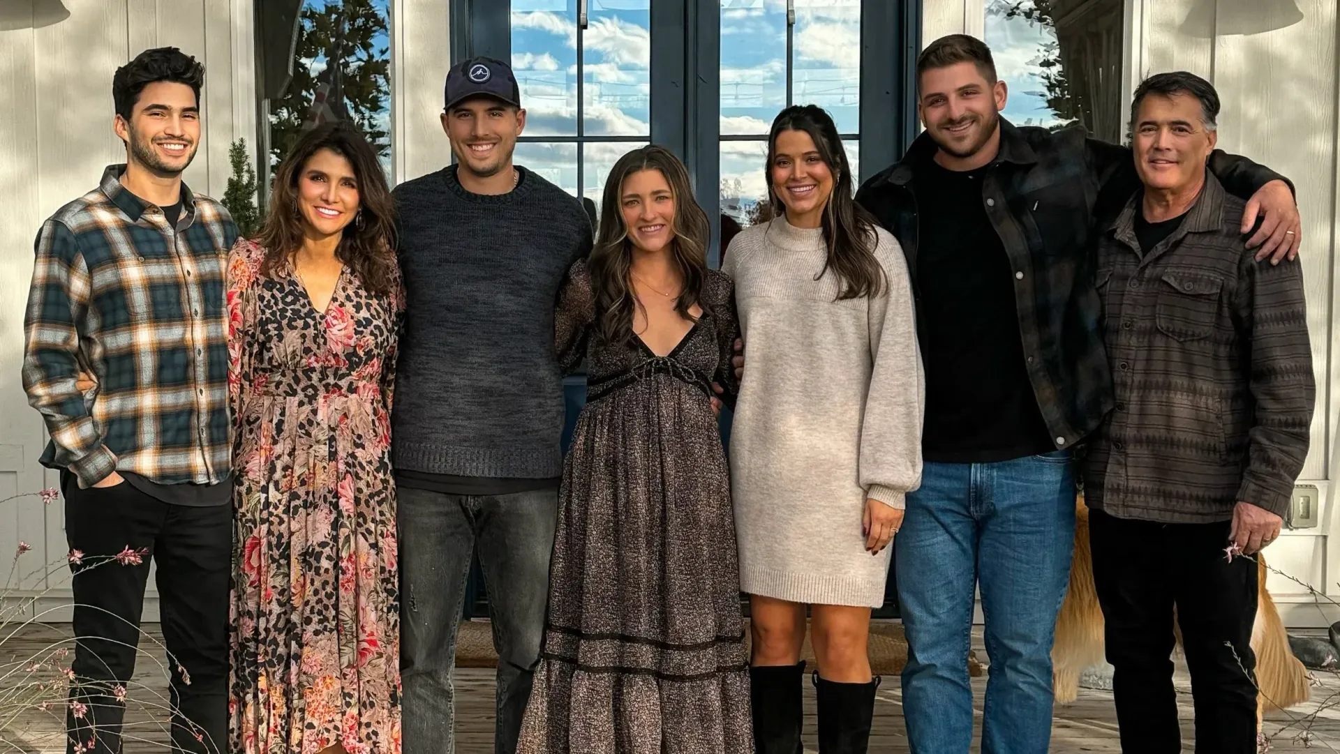 Seven people standing indoors, smiling at the camera in casual clothes.