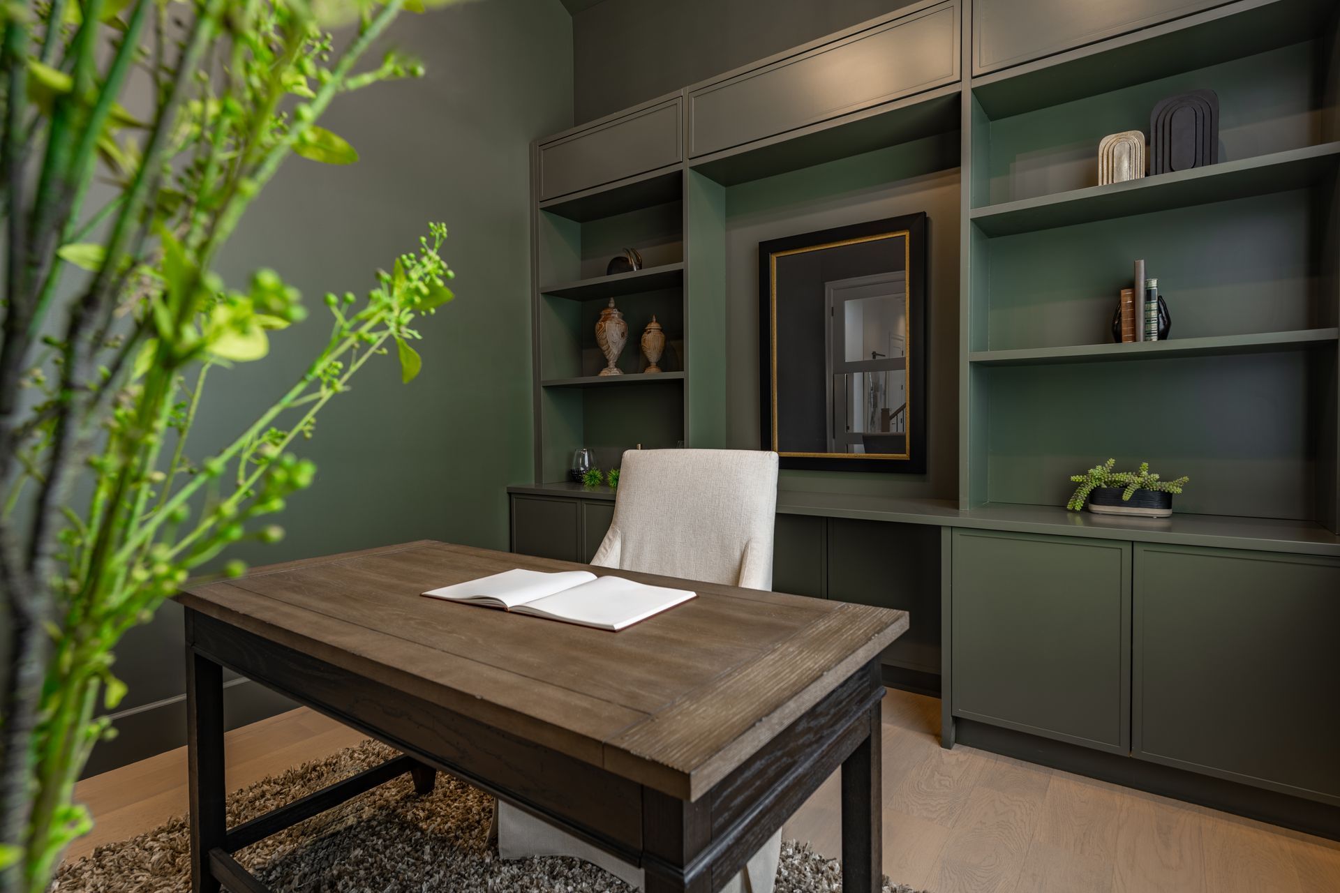 Modern office with a wooden desk, white chair, and built-in sage green shelving