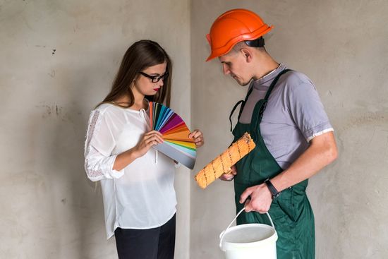 A man and a woman are standing next to each other looking at a color palette.