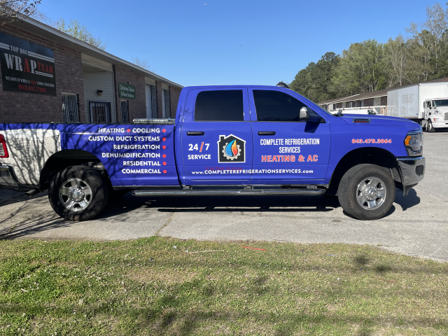 Blue branded pickup truck with emergency contact text parked outside a building.